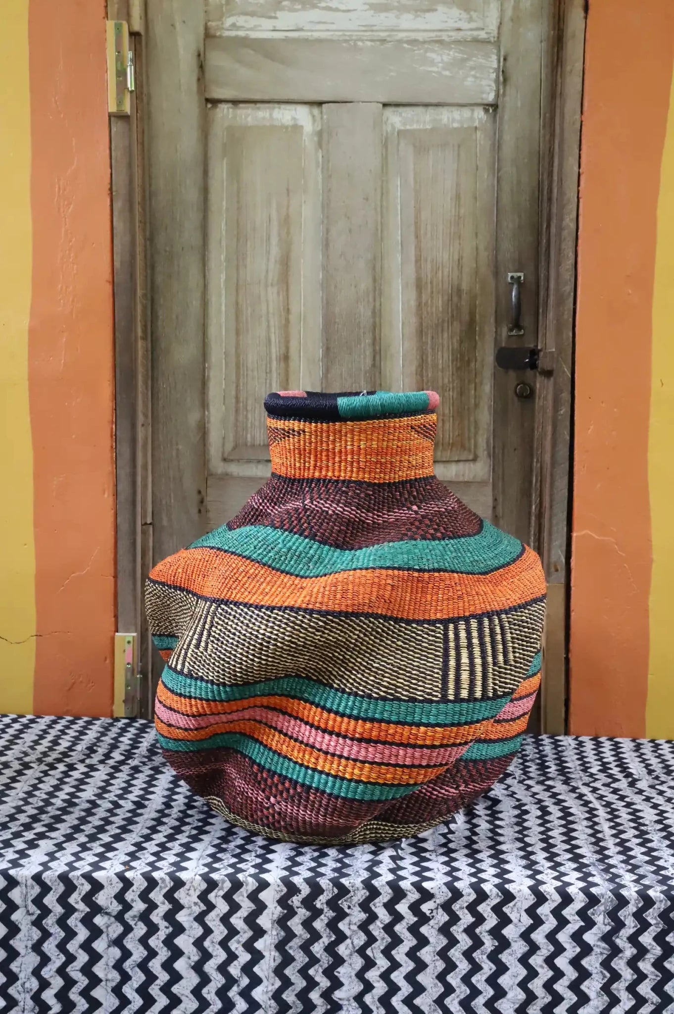 Colorful woven basket against a wooden door.