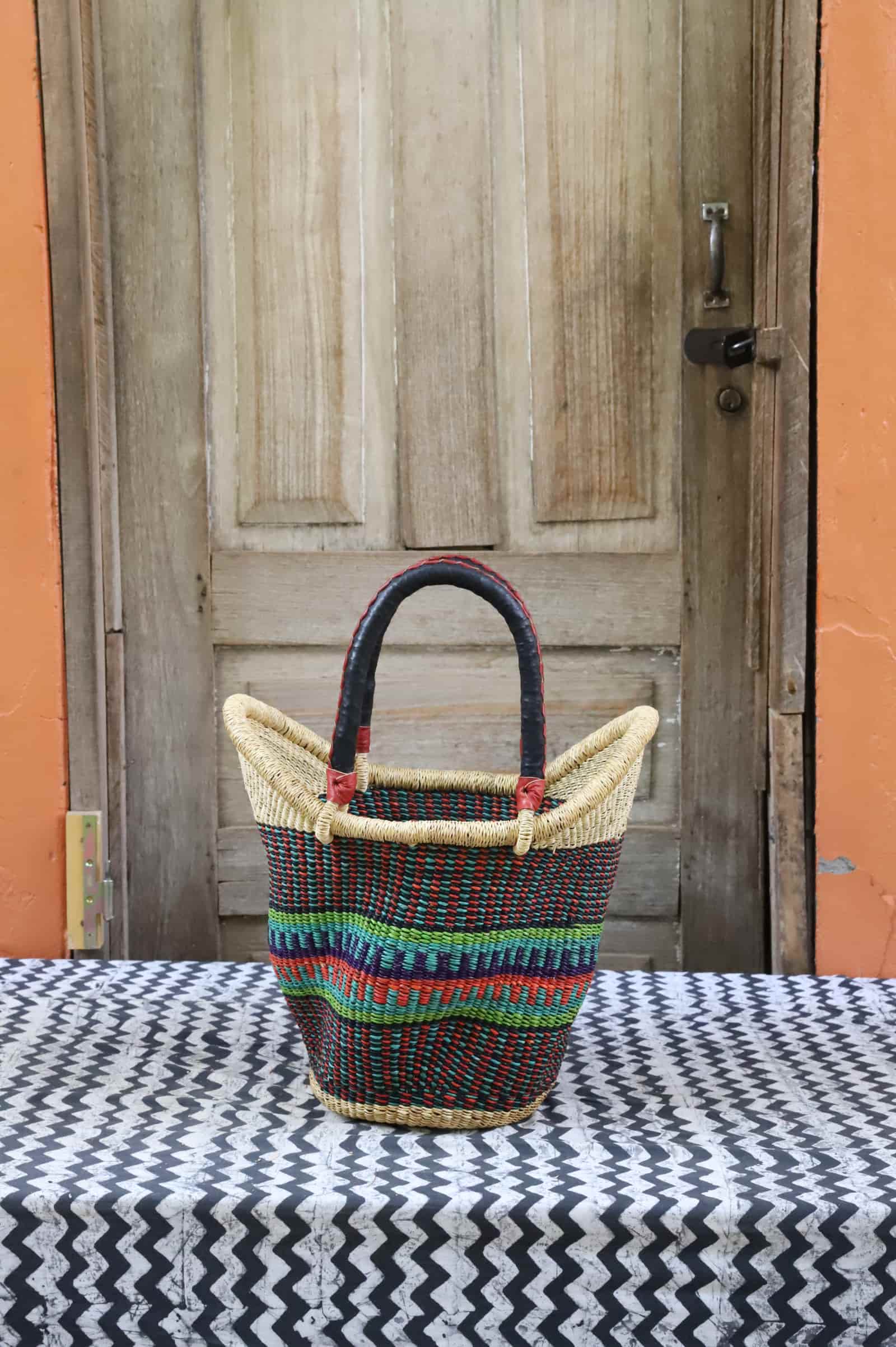 Woven carry on basket with premium leather on a black and white cloth against a wooden door