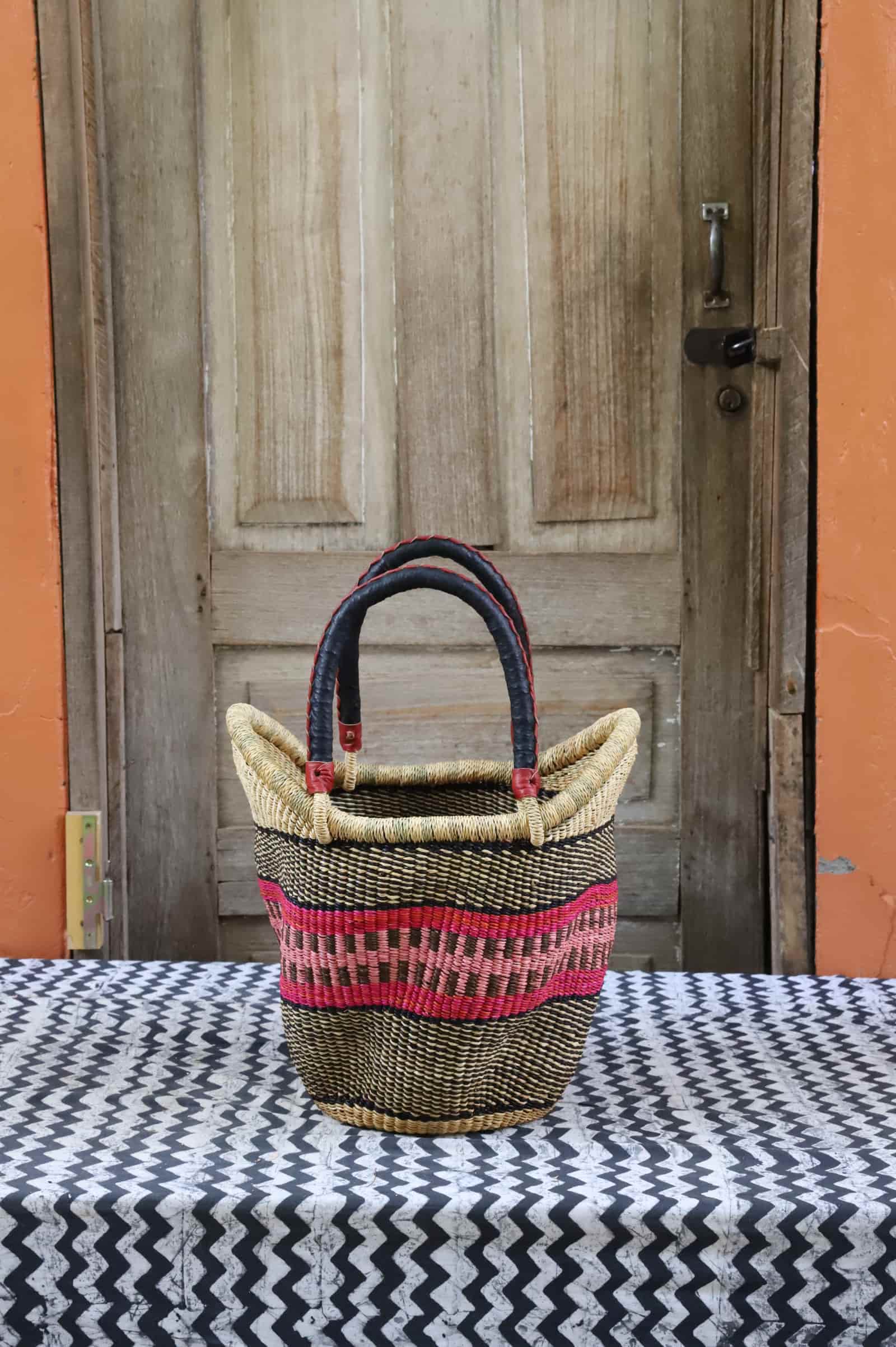 Woven carry on basket with premium leather on a black and white cloth against a wooden door