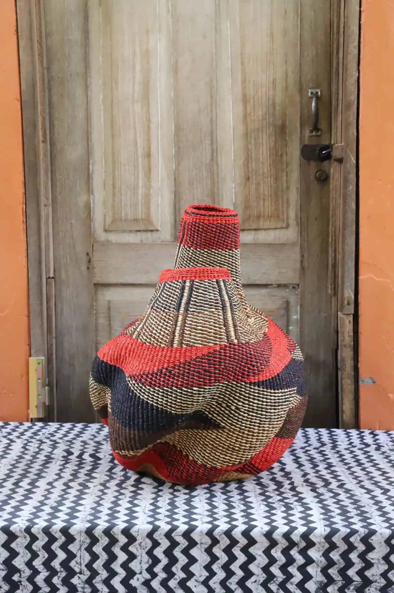 Decorative basket  on a black and white cloth against a wooden door.