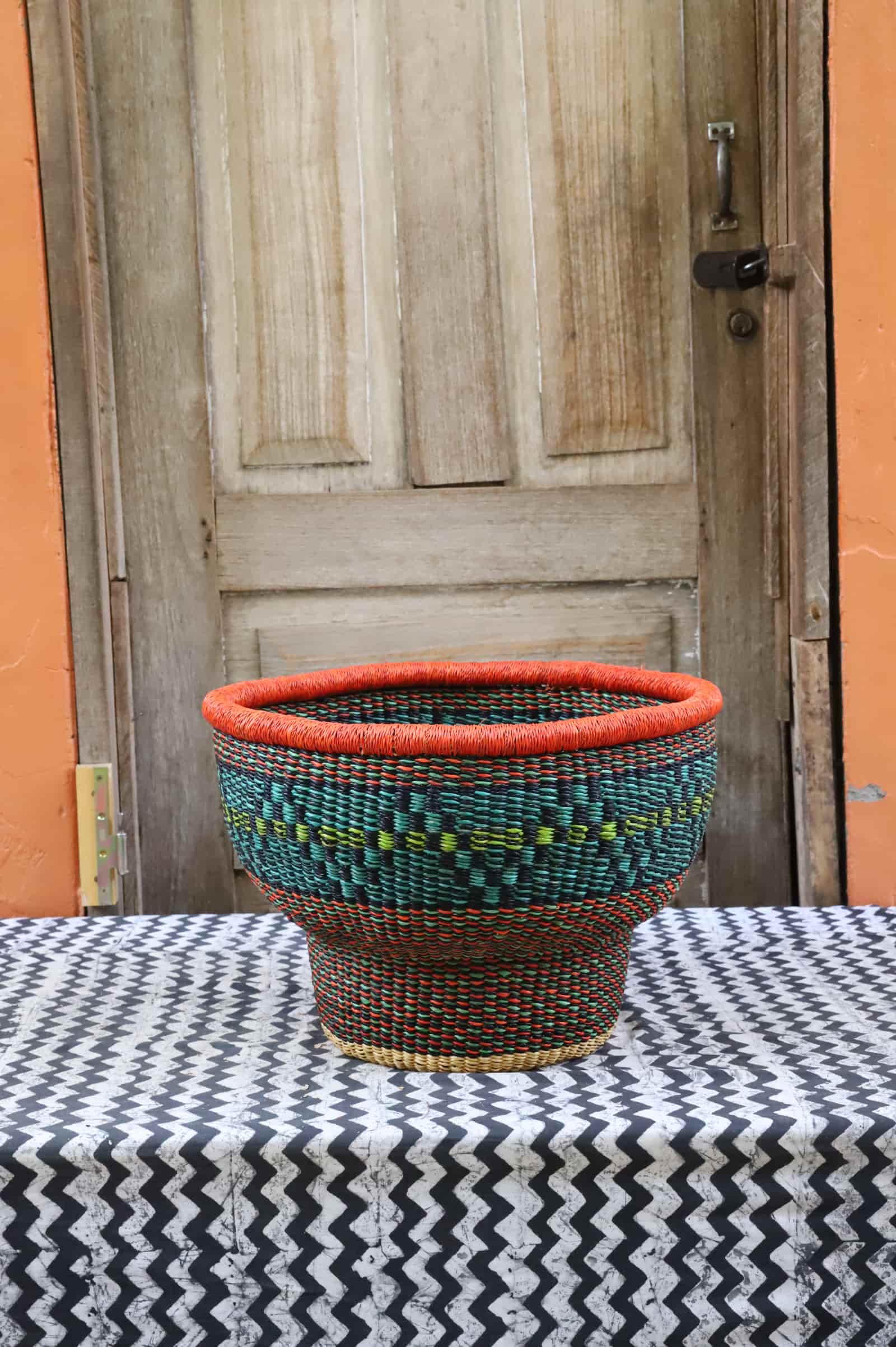 Woven storage basket with a beautiful pattern on a black and white cloth against a wooden door.