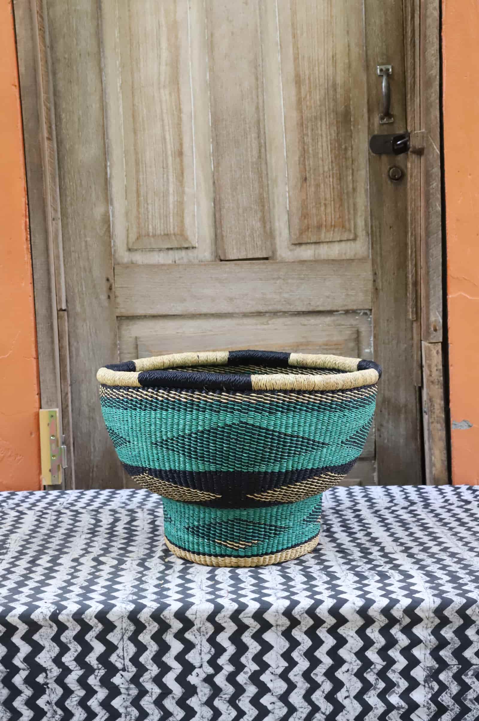 Woven storage basket with a beautiful pattern on a black and white cloth against a wooden door.