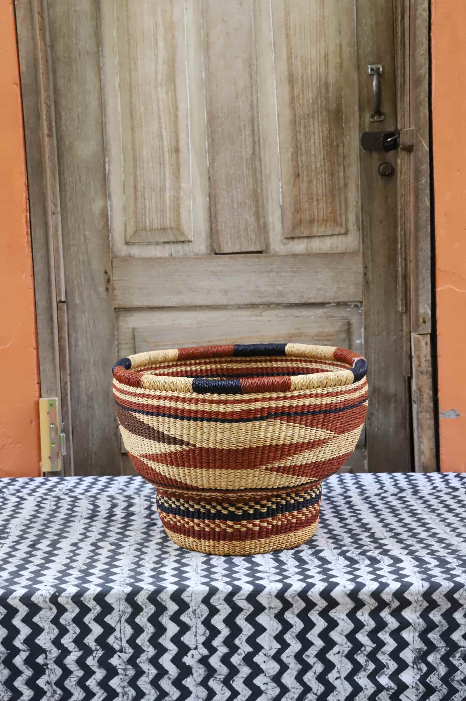 Woven storage basket with a beautiful pattern on a black and white cloth against a wooden door.