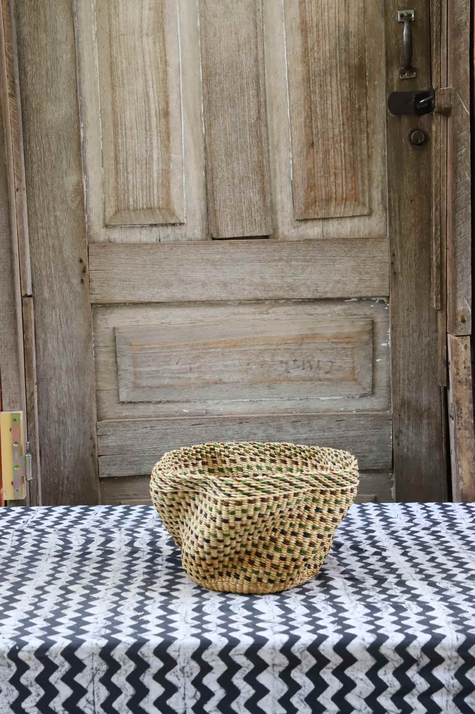 Woven basket on a table with a wooden door in the background