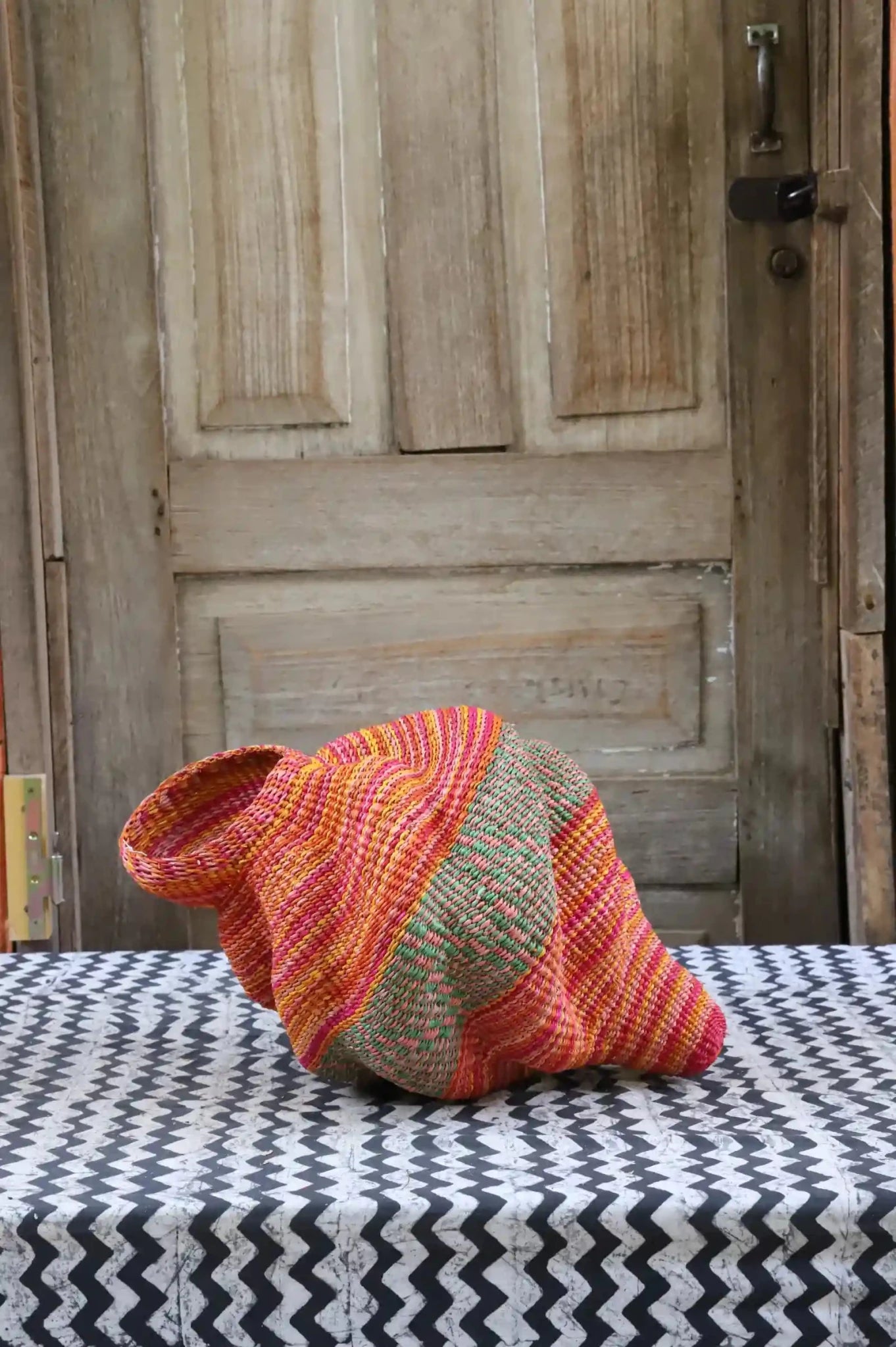 Colorful conch-shaped piece on a black and white cloth against a wooden door.