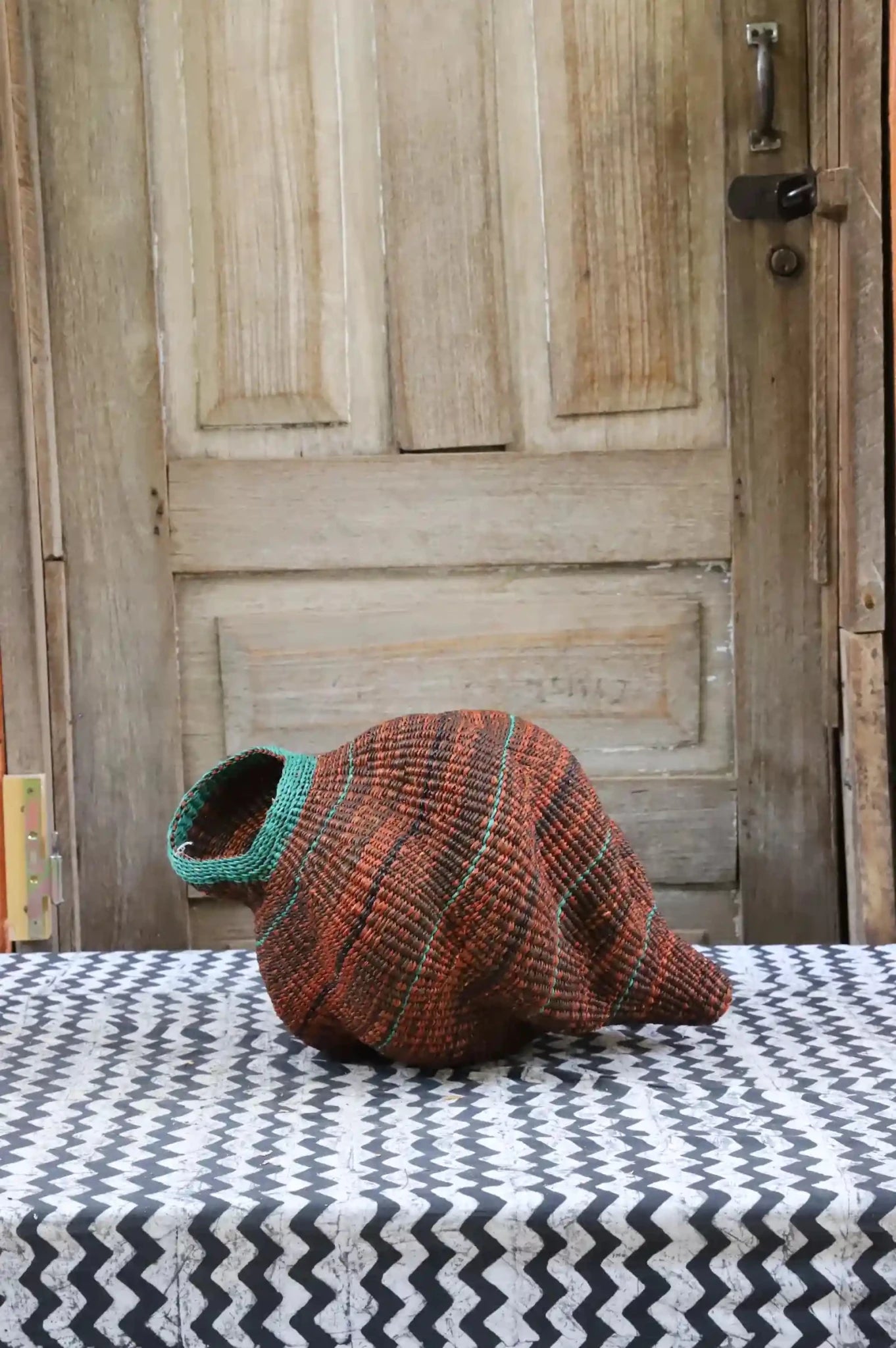 Colorful conch-shaped piece on a black and white cloth against a wooden door.