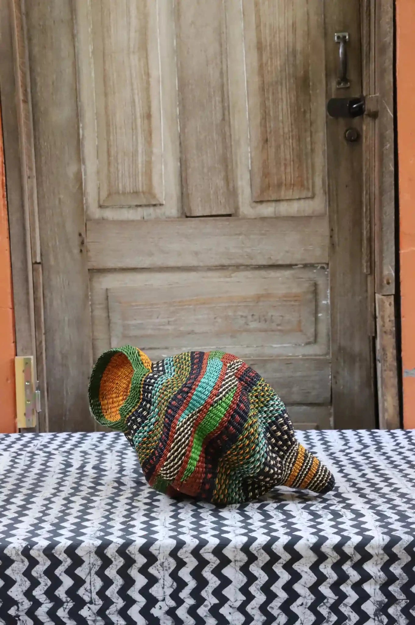 Colorful conch-shaped piece on a black and white cloth against a wooden door.