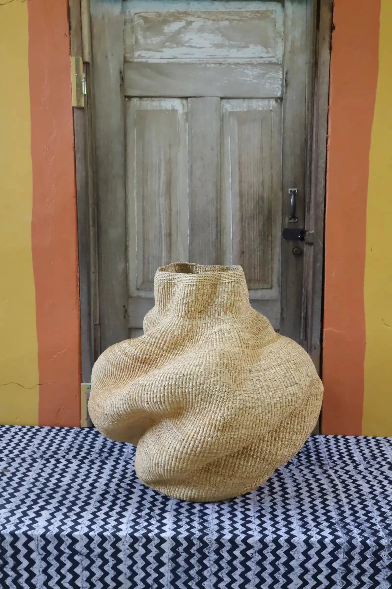 Decorative basket  on a black and white cloth against a wooden door.