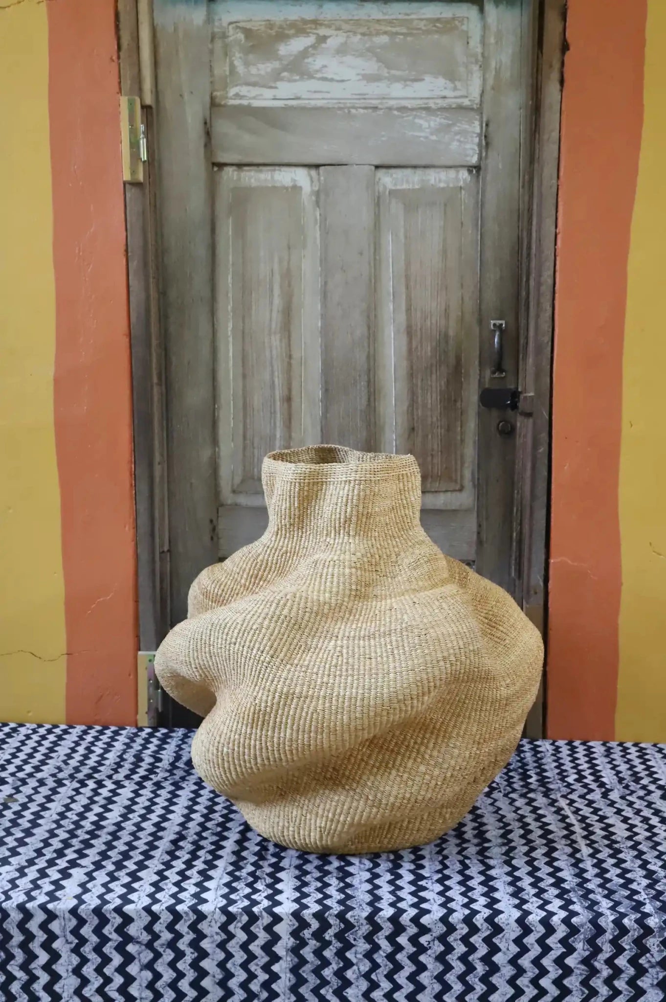 Decorative basket  on a black and white cloth against a wooden door.