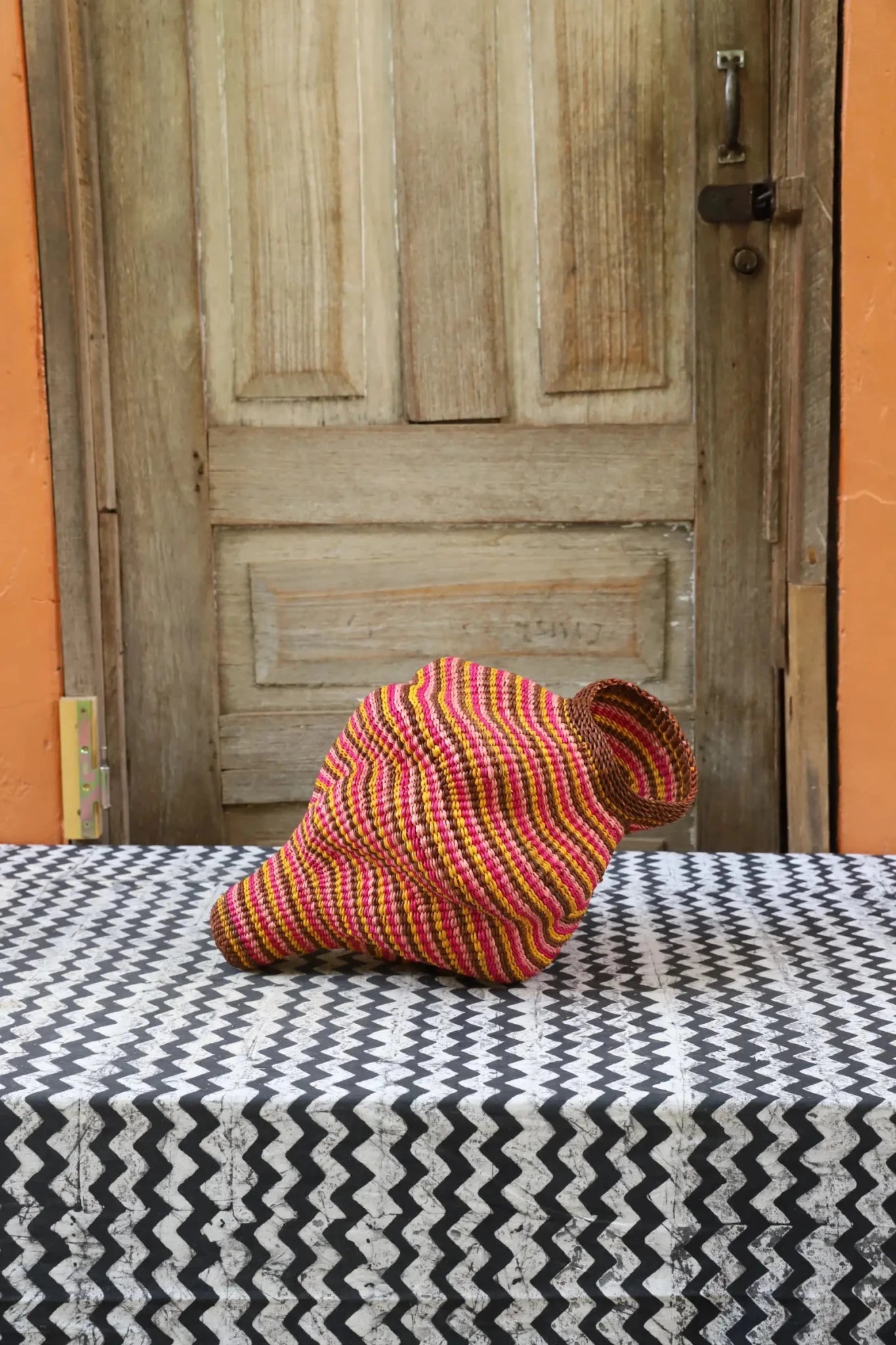 Colorful conch-shaped piece on a black and white cloth against a wooden door.