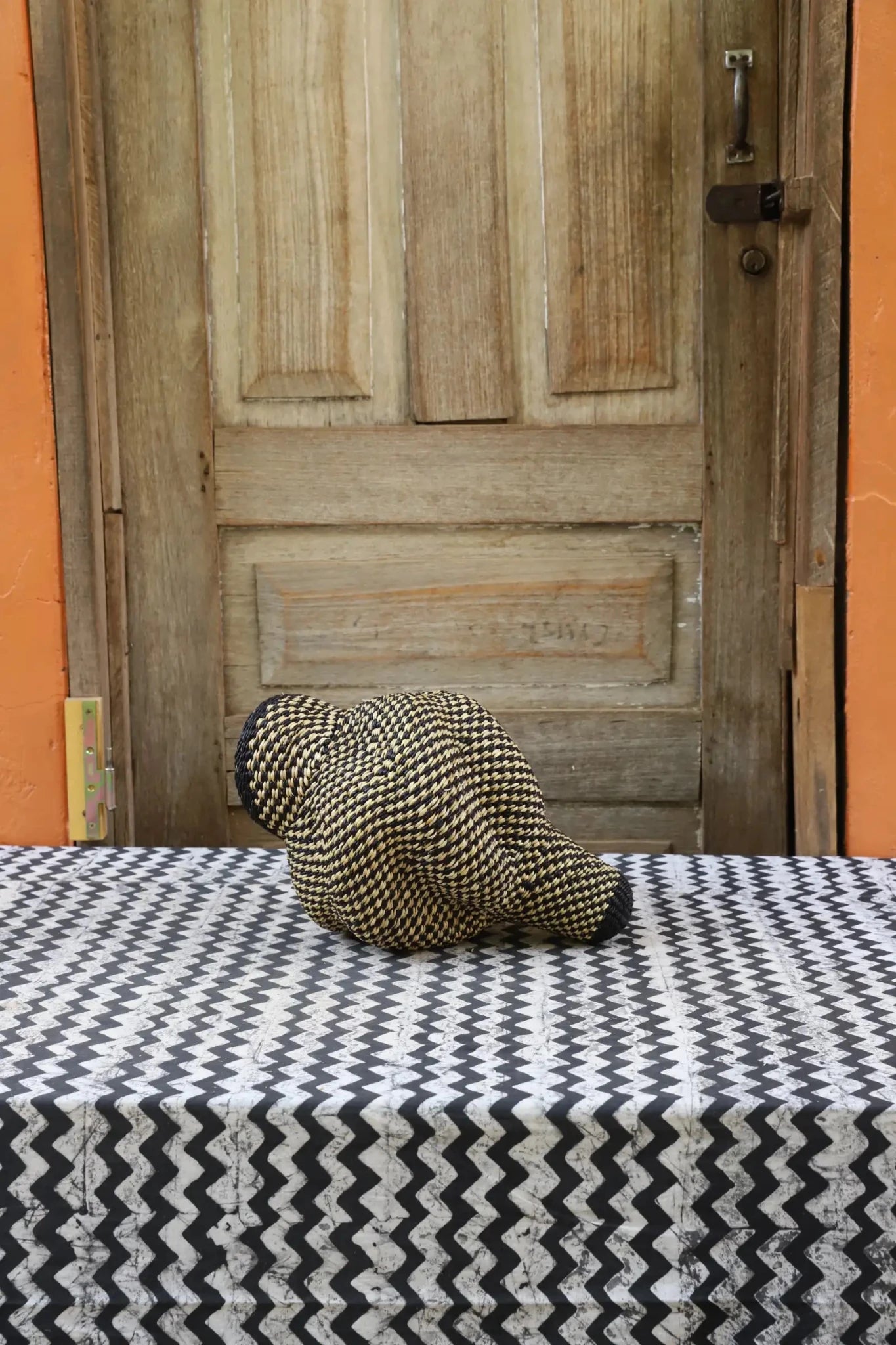 Patterned conch-shaped piece on a black and white cloth against a wooden door.