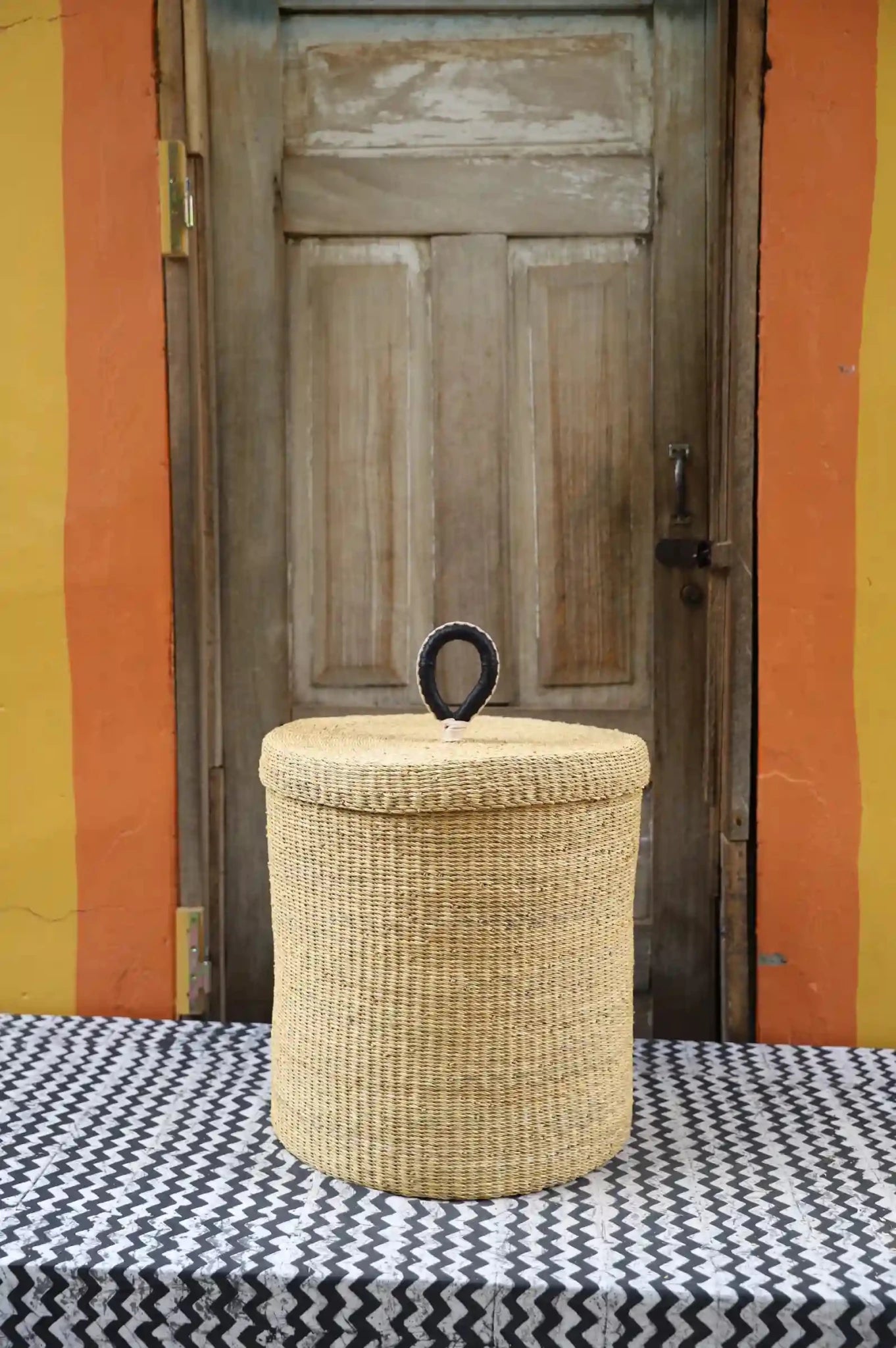 Lidded Laundry Basket (Medium) by The Baba Tree. Handwoven elephant grass with leather handle. Premium Bolgatanga artisan decor.l