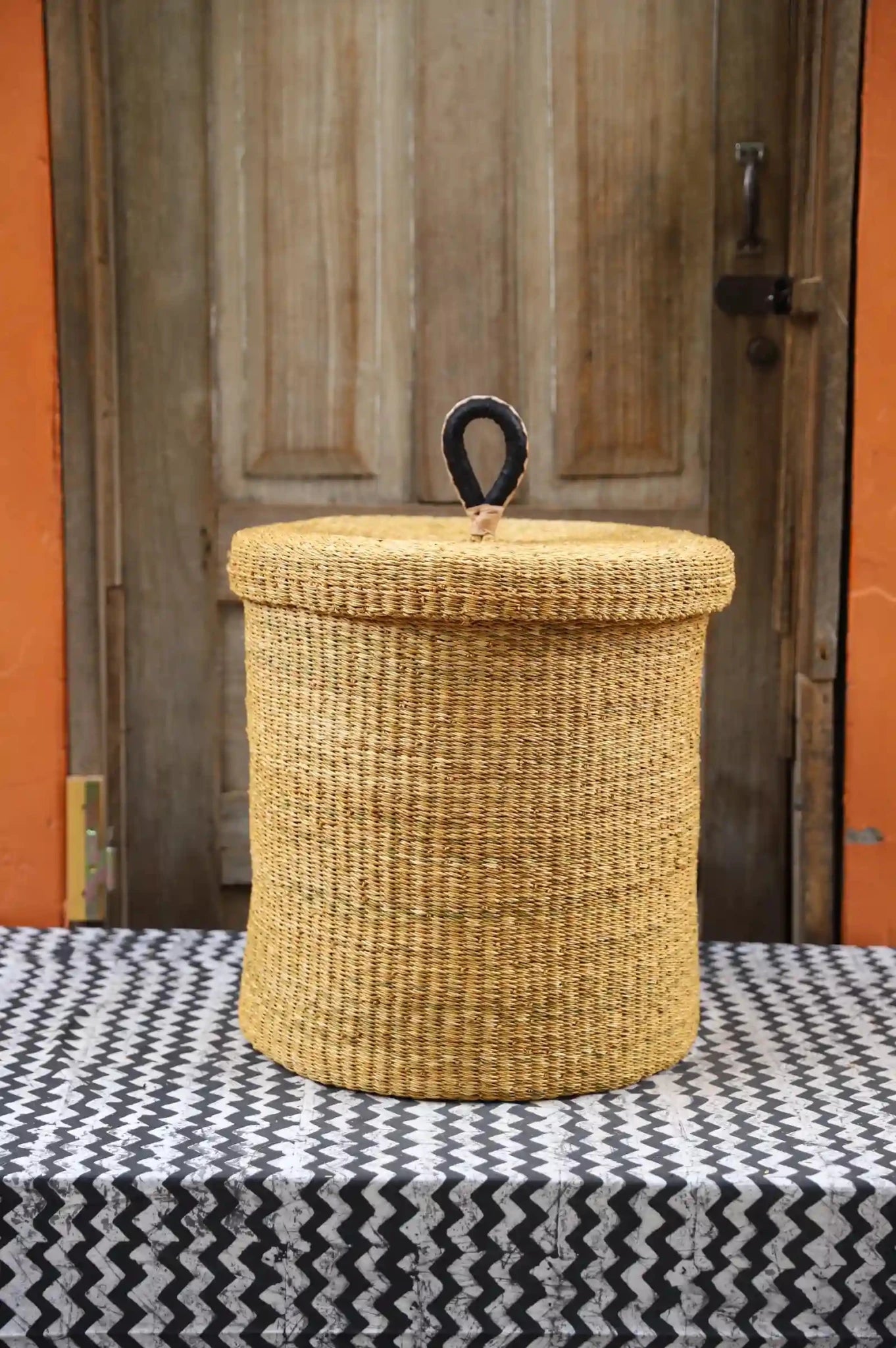 Lidded Laundry Basket (Medium) by The Baba Tree. Handwoven elephant grass with leather handle. Premium Bolgatanga artisan decor.l