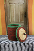 Lidded laundry basket in solid rust-red weave, lid resting alongside showing the straw underside.