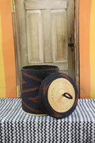 Lidded laundry basket in dark brown elephant grass, lid resting alongside showing the straw underside.