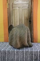 Large sculptural Bolga basket in a dense woven spiral form, natural straw, shown from behind on a chevron cloth.