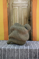 Spiral-form Bolga basket in natural straw, side view showing the curved tail detail.