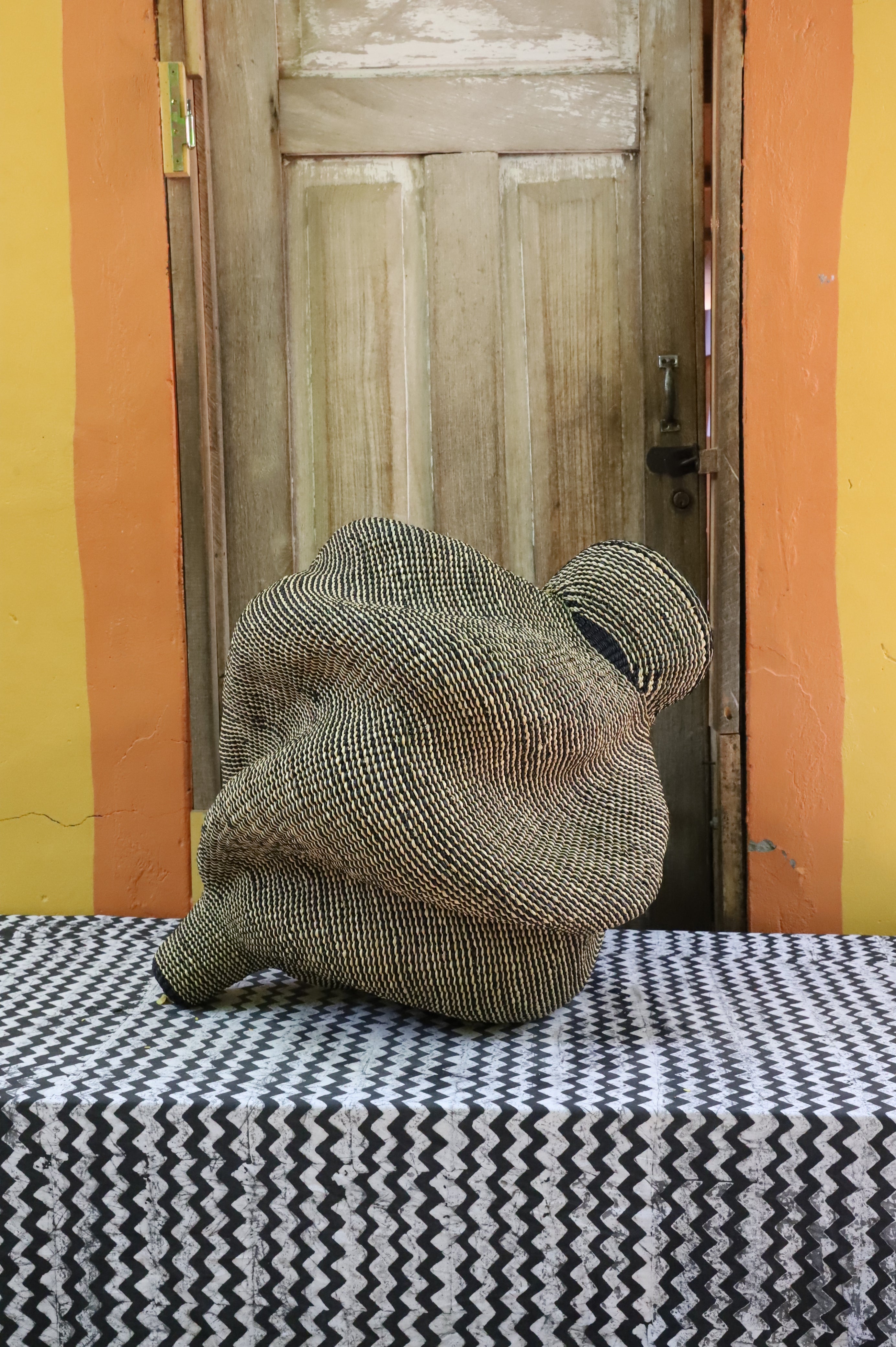 Spiral-form Bolga basket in natural straw, side view showing the curved tail detail.