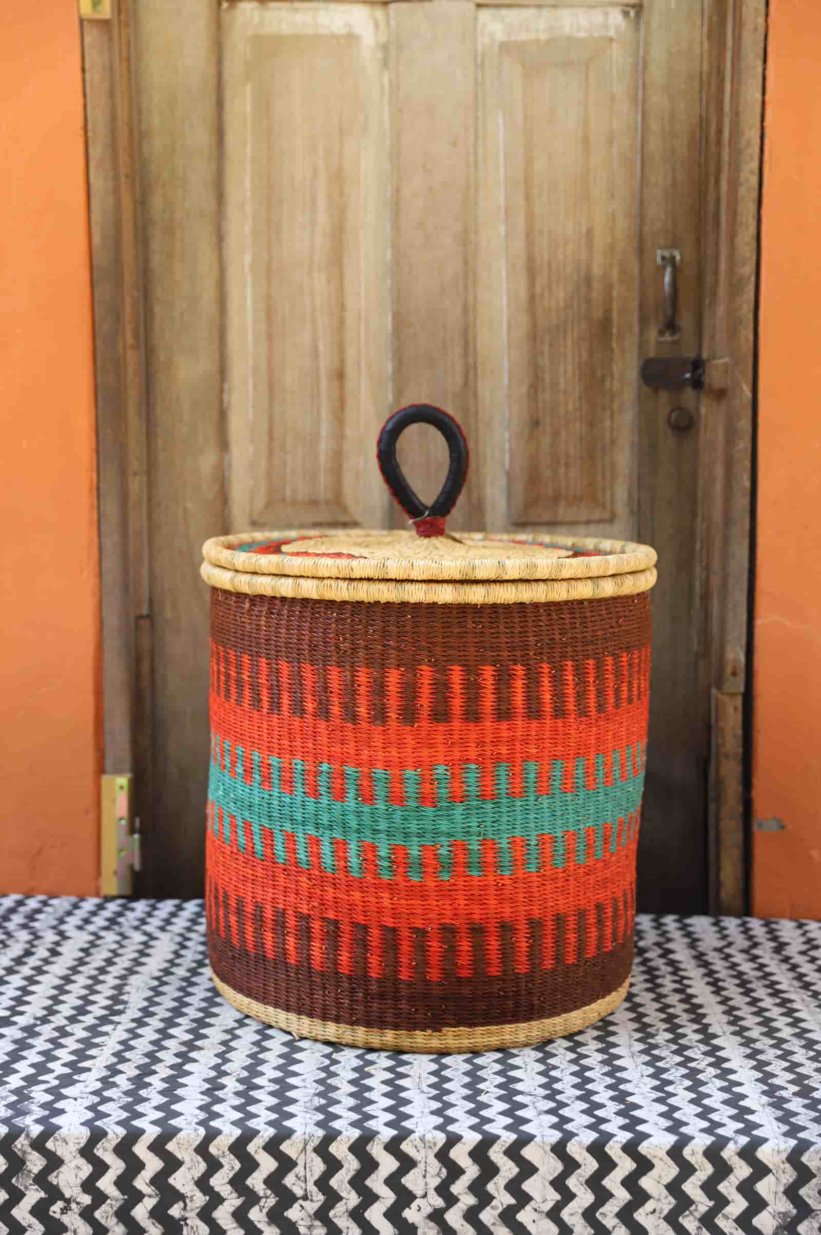 Woven basket with colorful stripes on a table with a wooden door in the background