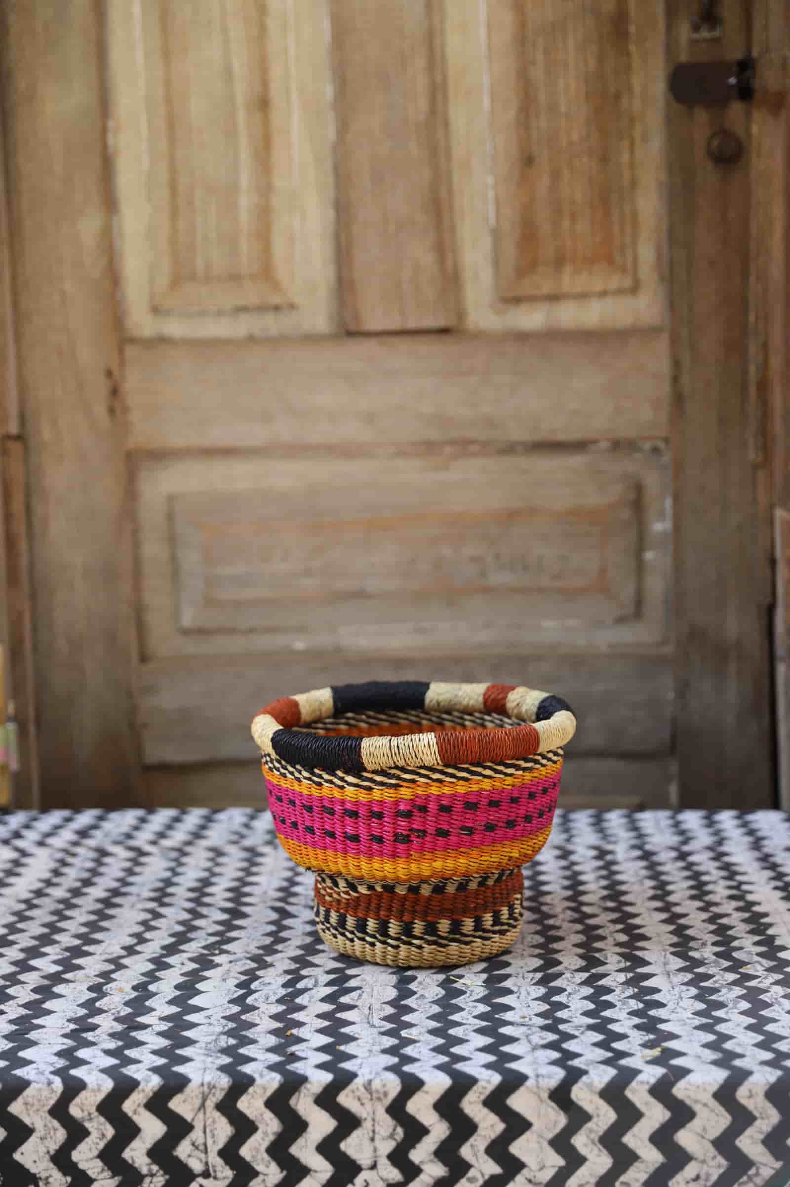 Woven storage basket with a beautiful pattern on a black and white cloth against a wooden door.