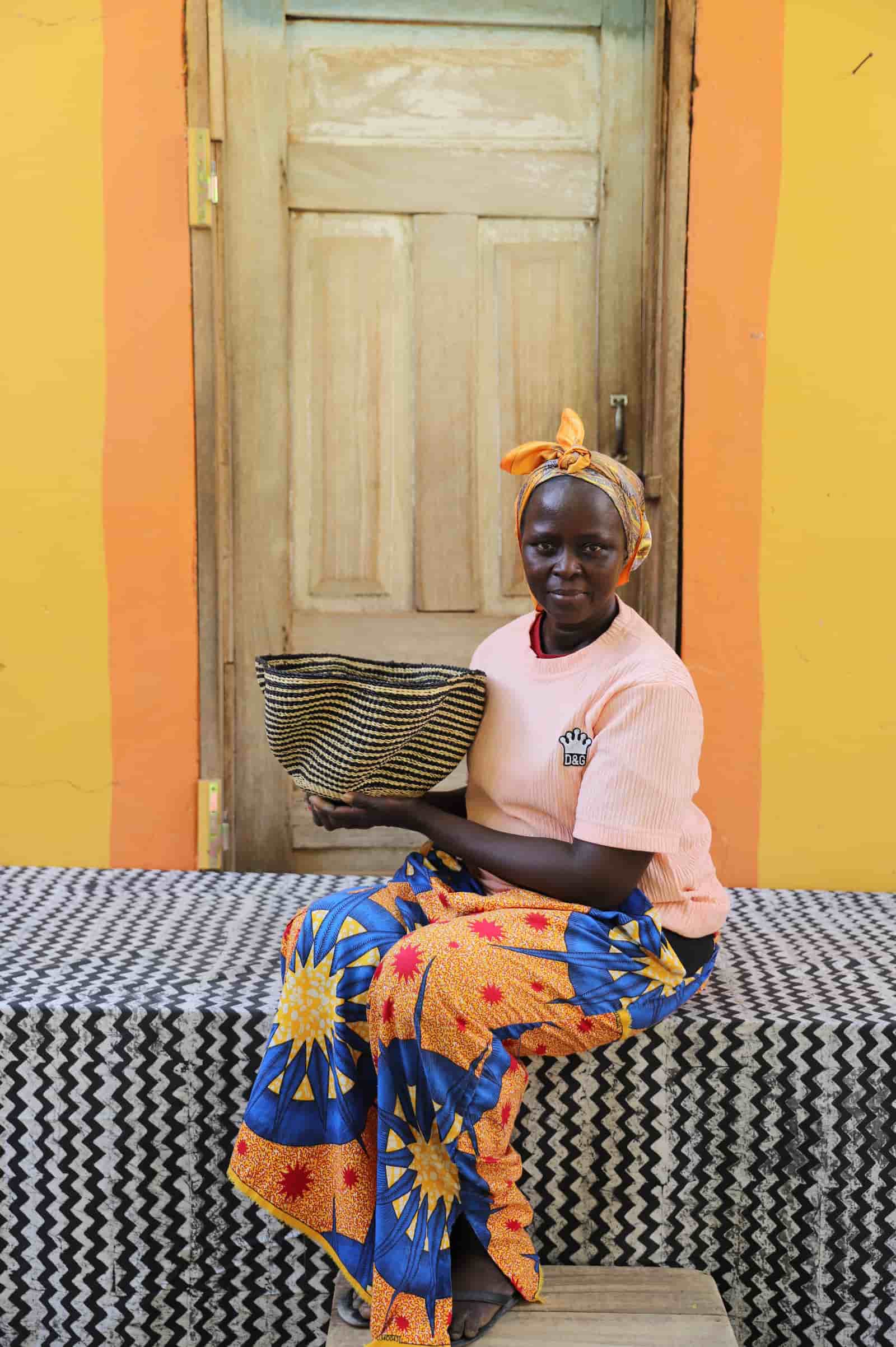 Woman holding tiny Pakurigo Wave Décor Basket with bold black and natural straw stripe pattern