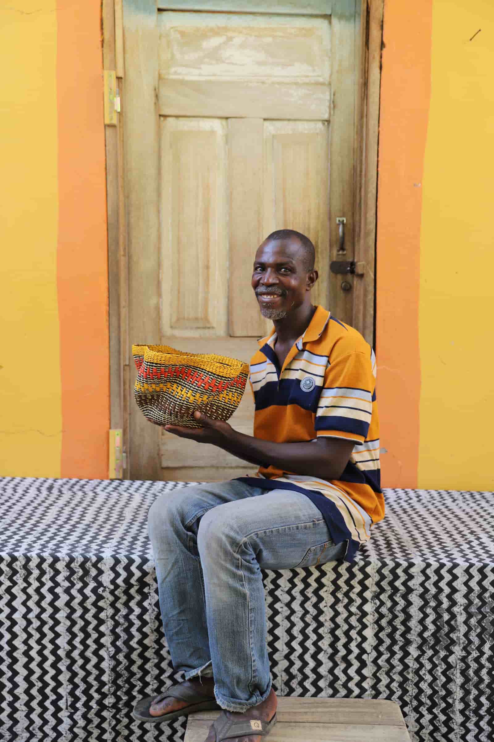 Man holding tiny Pakurigo Wave Décor Basket with amber and rust wave-stripe pattern