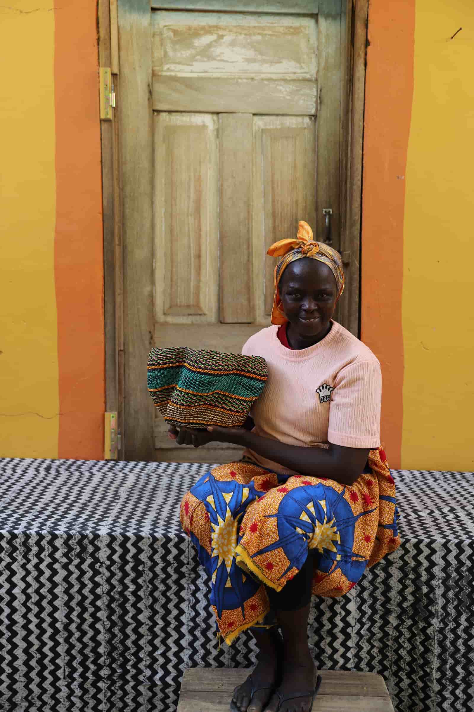 Woman holding tiny Pakurigo Wave Décor Basket with teal and amber wave stripe pattern