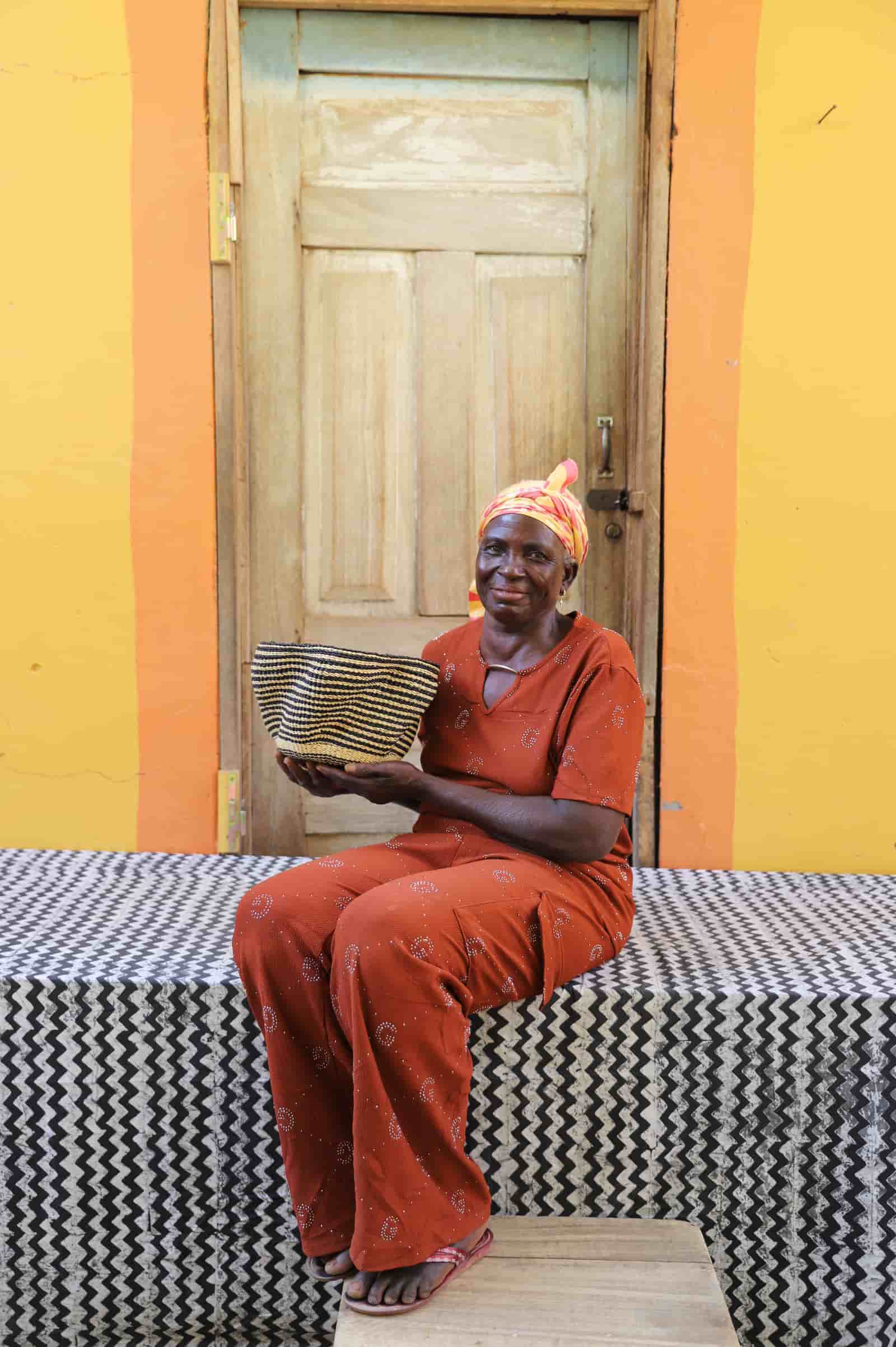 Woman in orange outfit sitting on a bench with a colorful background