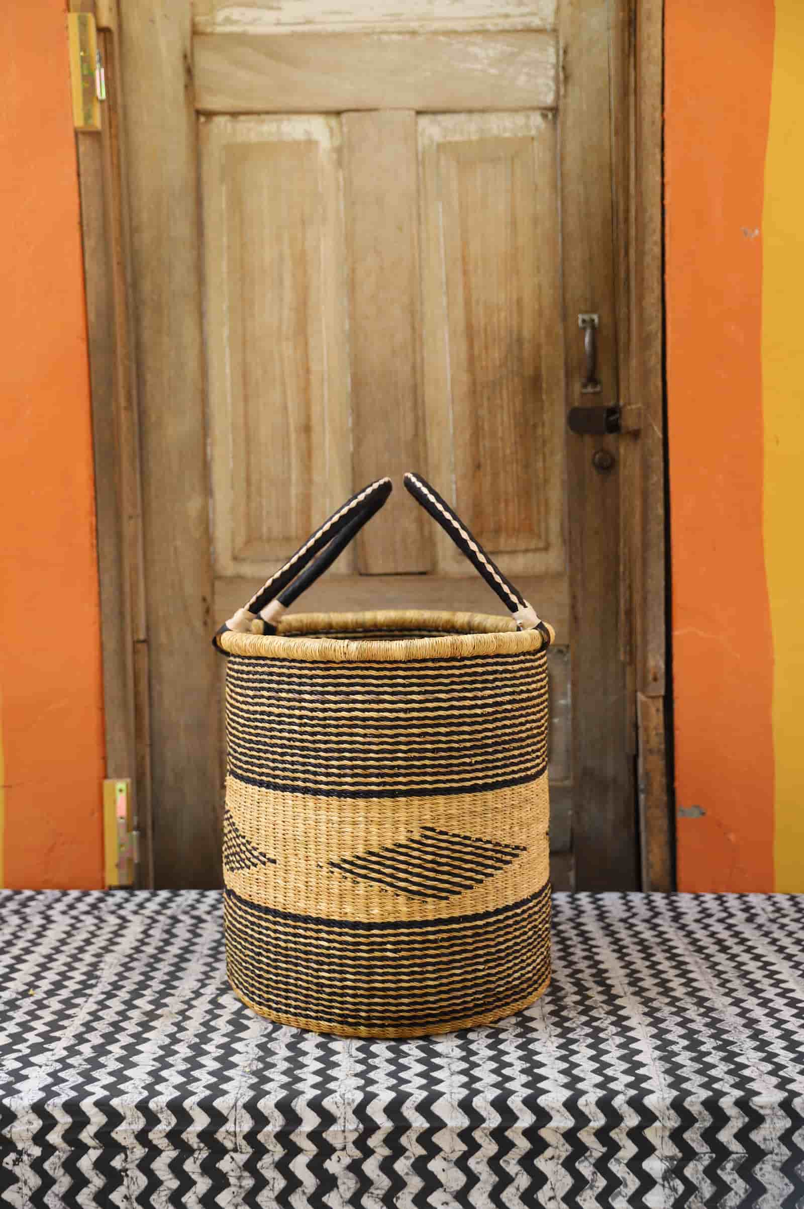 Open Laundry Basket by The Baba Tree. Handwoven elephant grass storage with leather handles. Bolgatanga artisan decor.