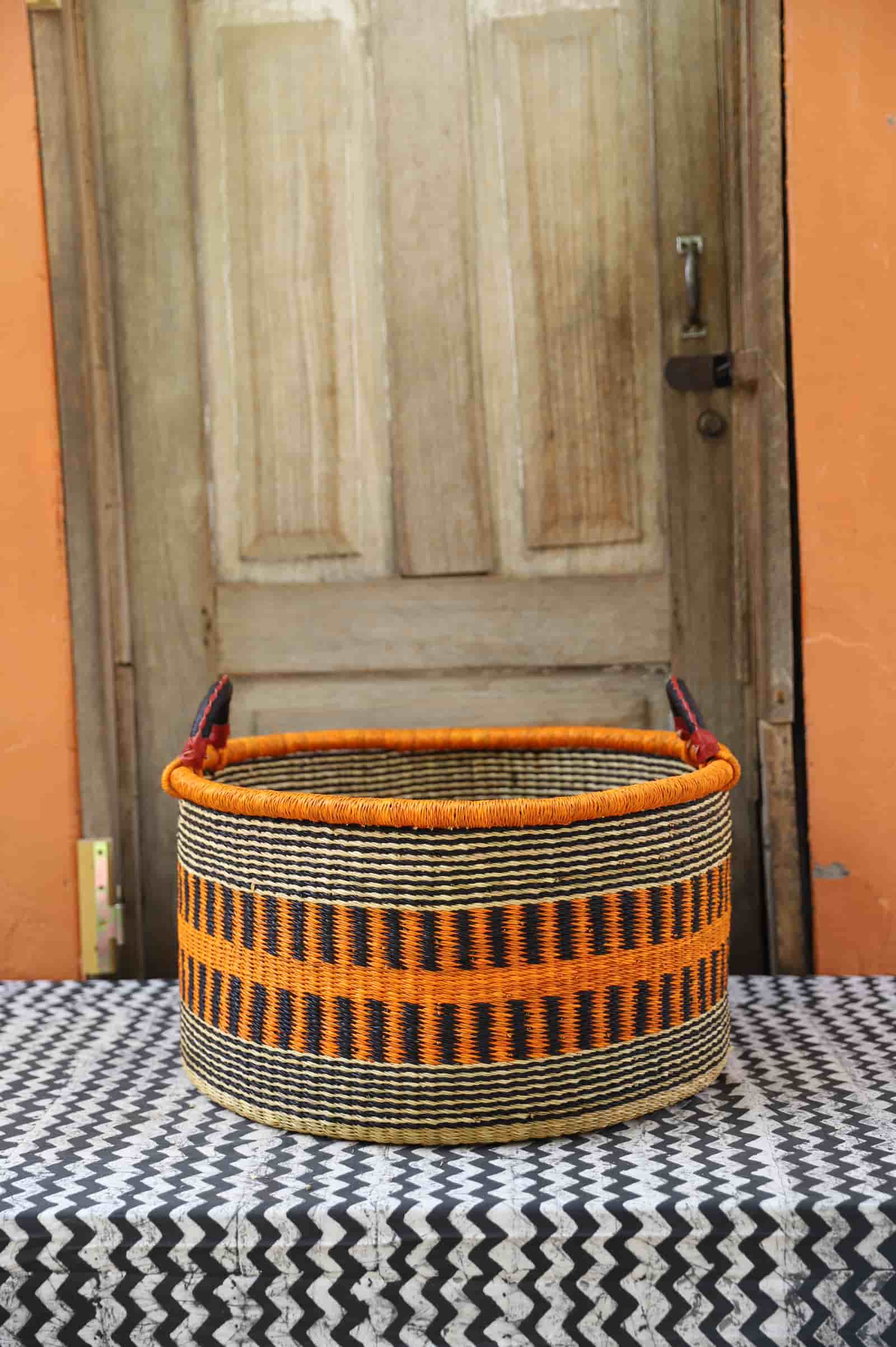 Woven Tub (Large) handwoven in Ghana sitting on black and white cloth with wooden door background

