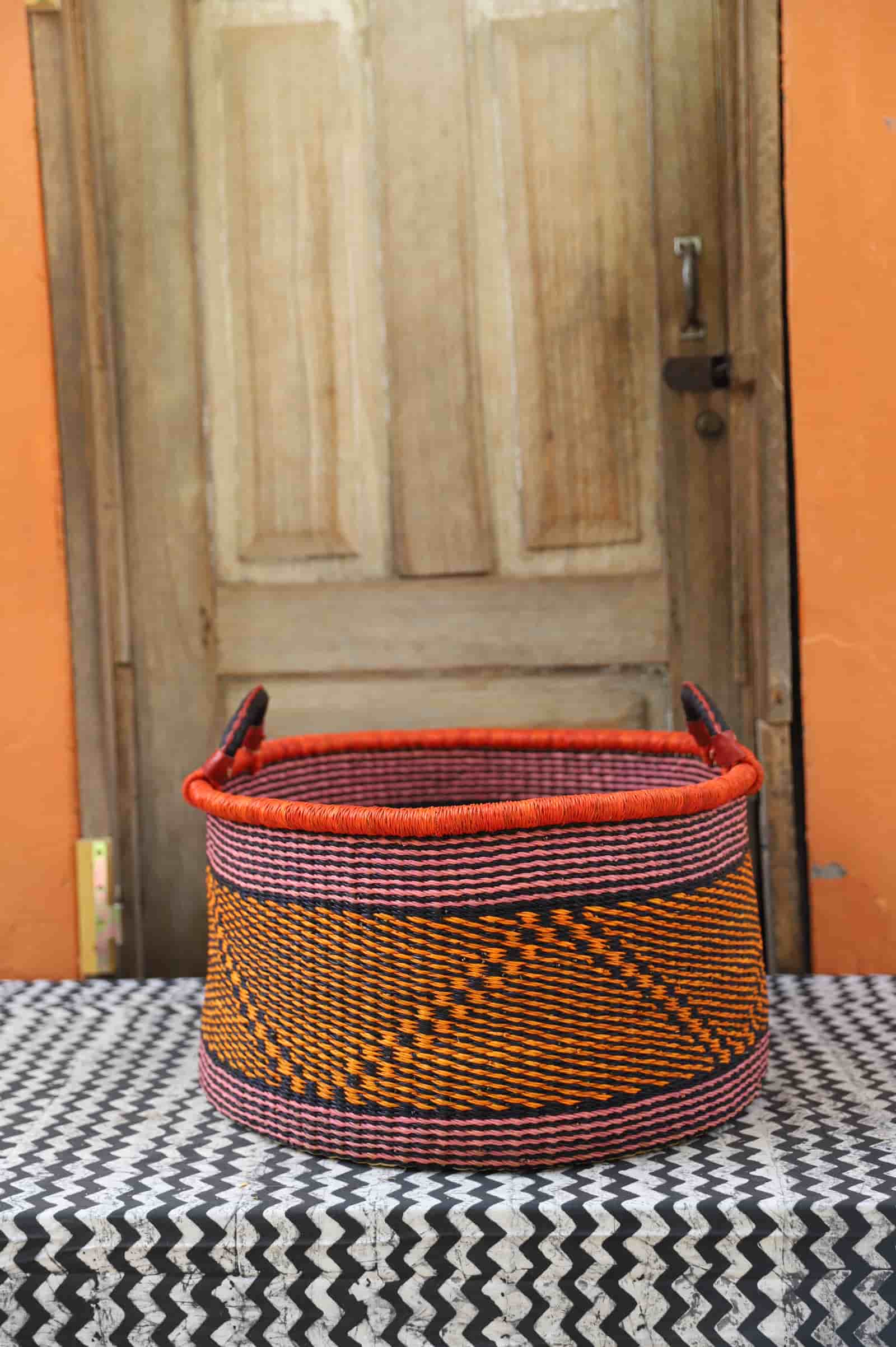Woven Tub (Large) handwoven in Ghana sitting on black and white cloth with wooden door background