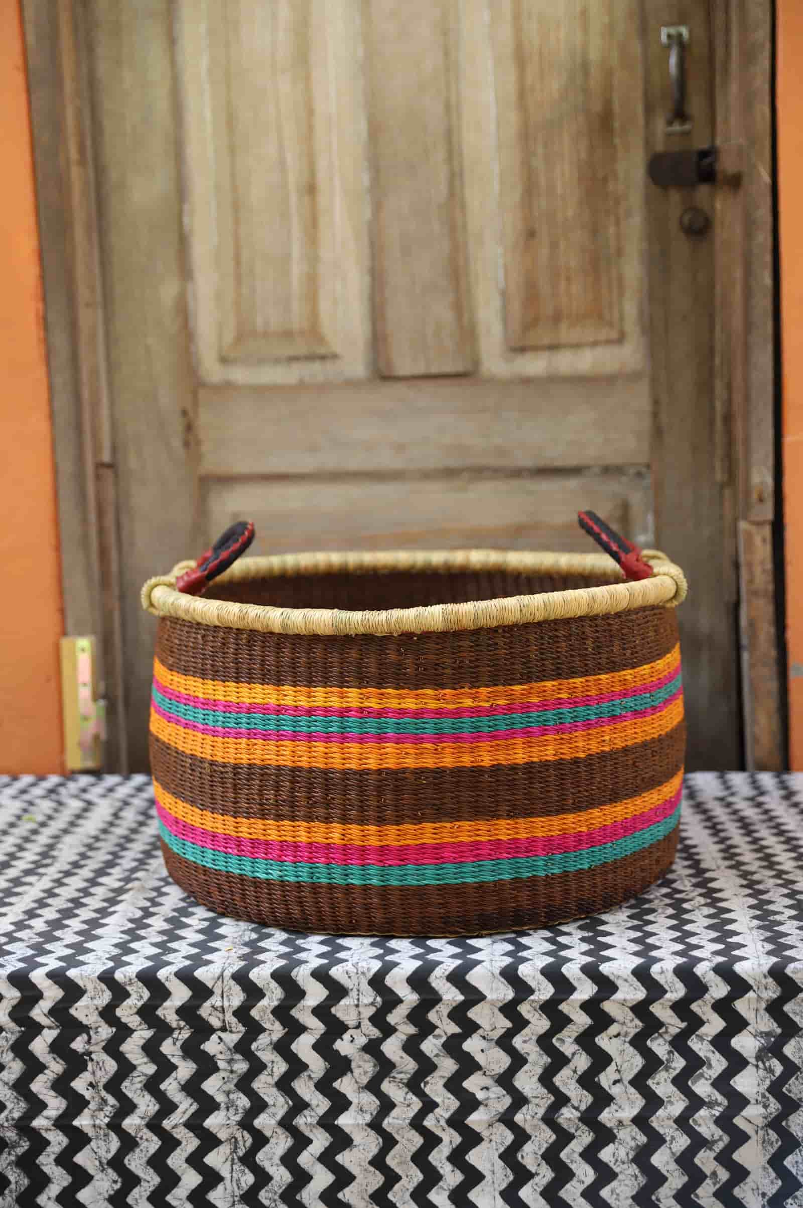 Woven Tub (Medium) handwoven in Ghana sitting on black and white cloth with wooden door background

