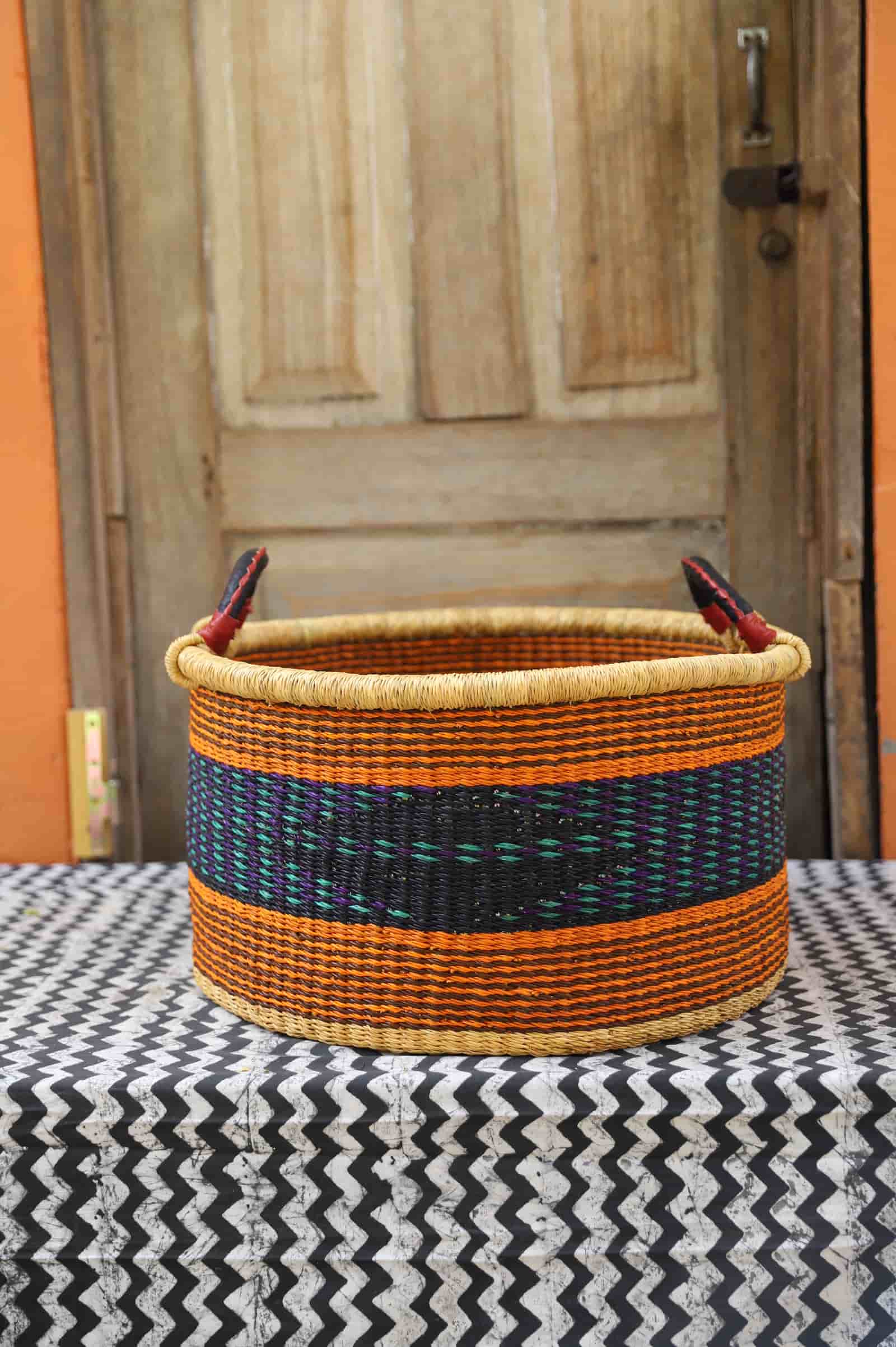 Woven Tub (Medium) handwoven in Ghana sitting on black and white cloth with wooden door background