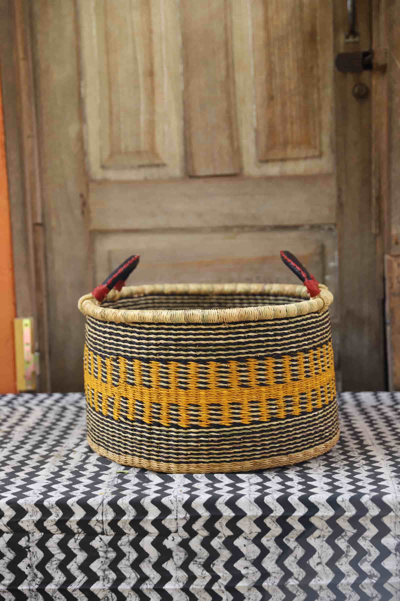 Woven Tub (Small) handwoven in Ghana sitting on black and white cloth with wooden door background

