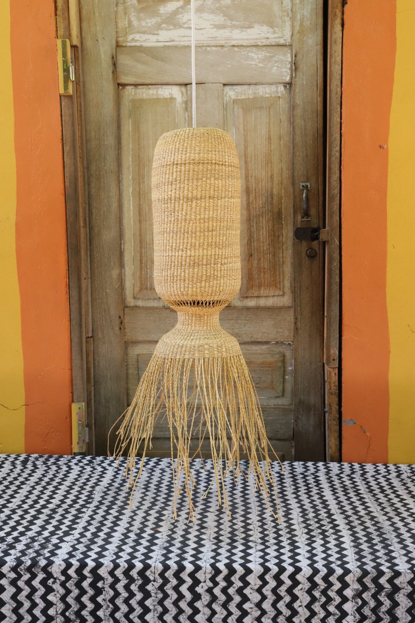 Woven basket  hanging against a wooden door with colorful striped background