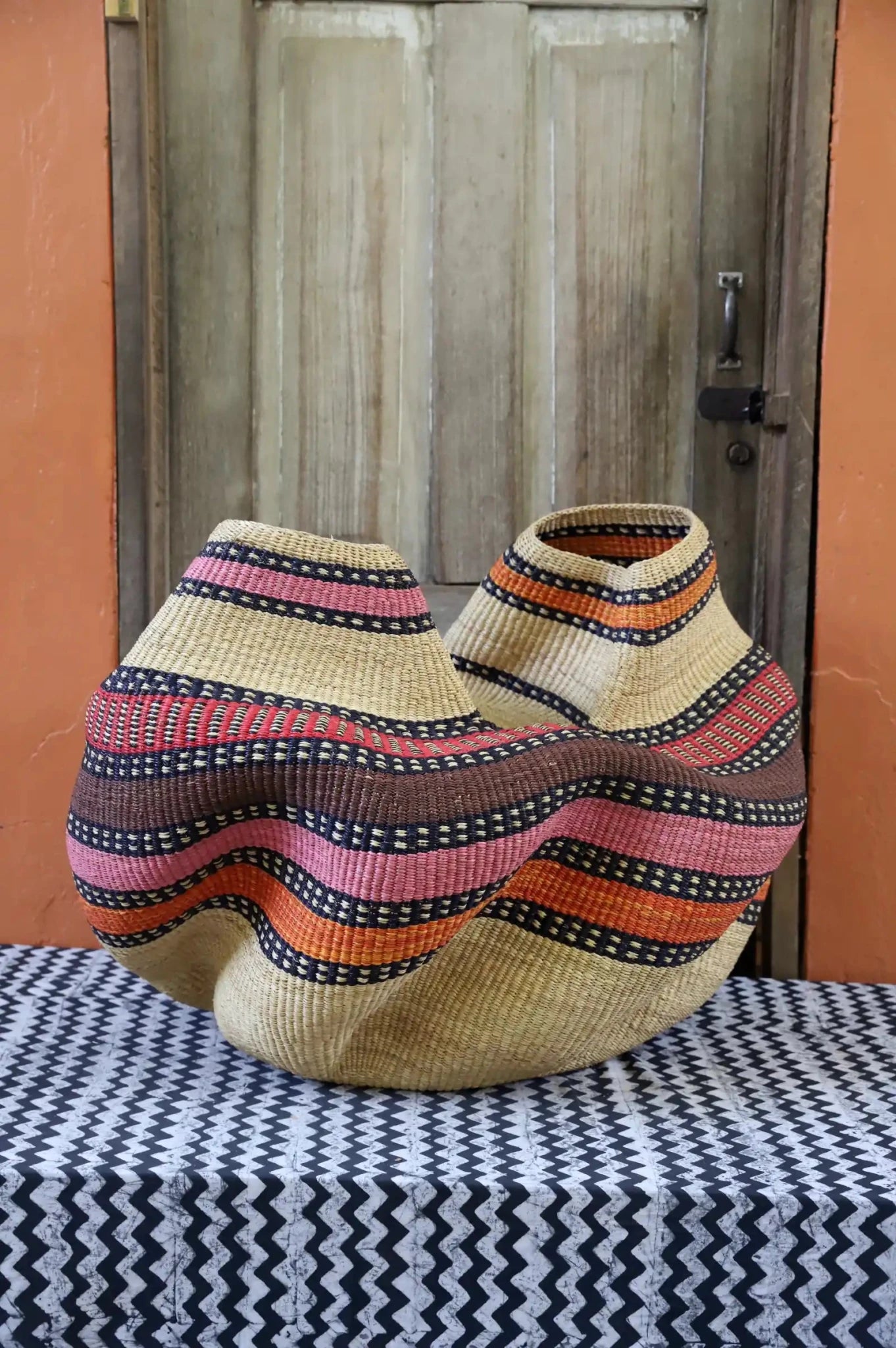 Decorative basket  on a black and white cloth against a wooden door.