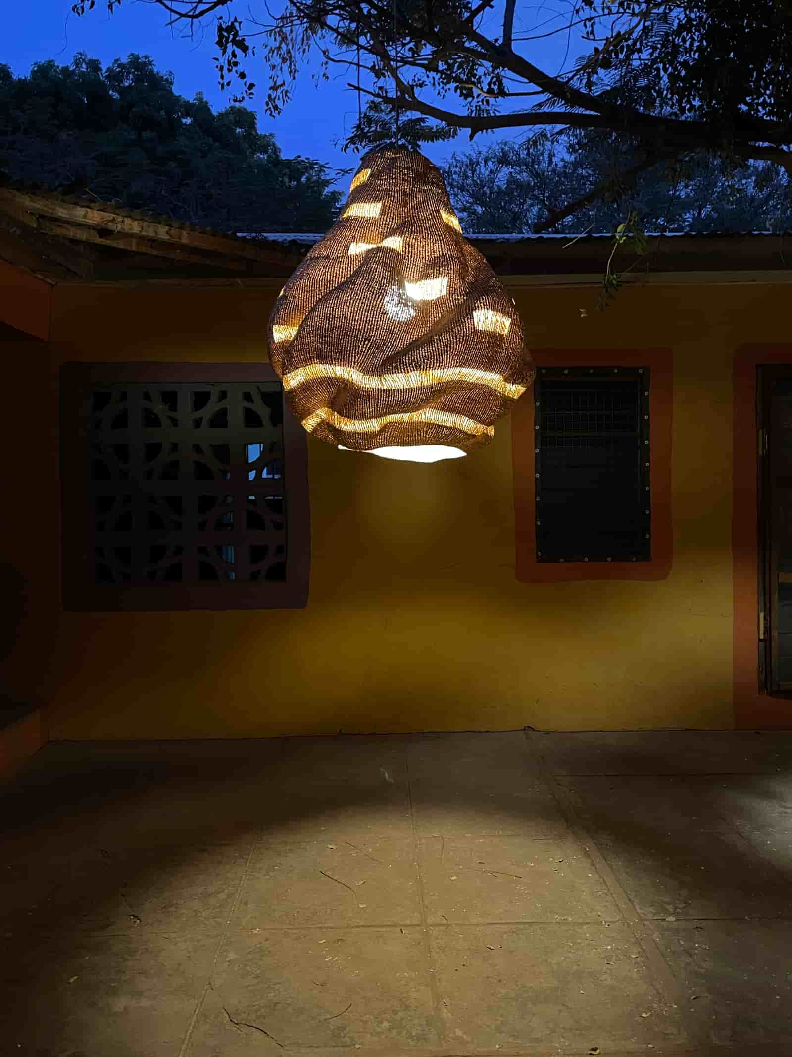 Hanging lamp with a unique design on a yellow wall at night.