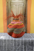 A colorful, handwoven piece sitting on a black and white cloth with decorative straw branching out. 