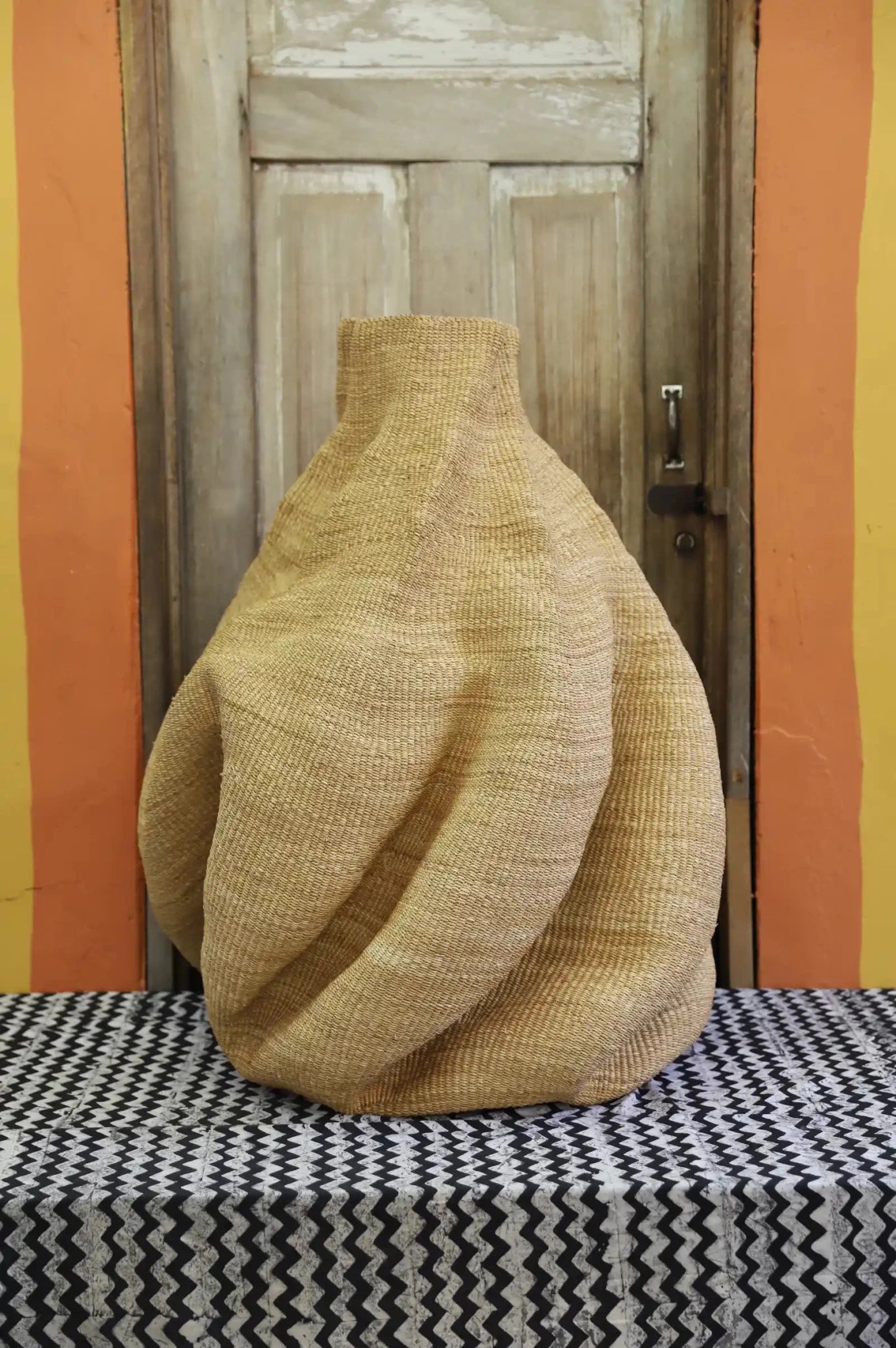 Decorative basket  on a black and white cloth against a wooden door.