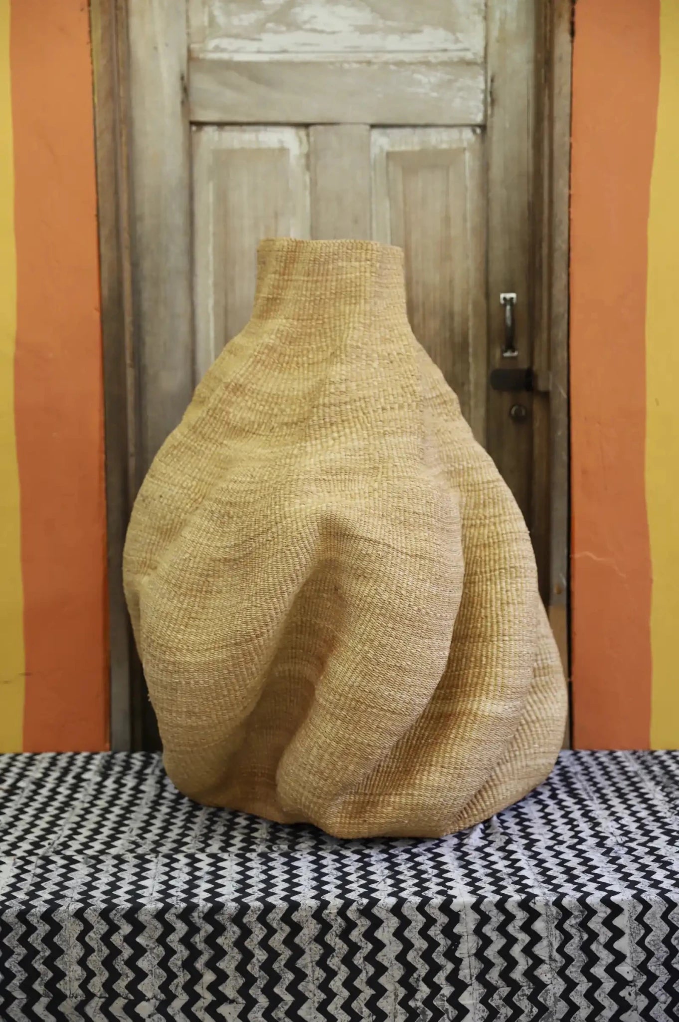 Decorative basket  on a black and white cloth against a wooden door.