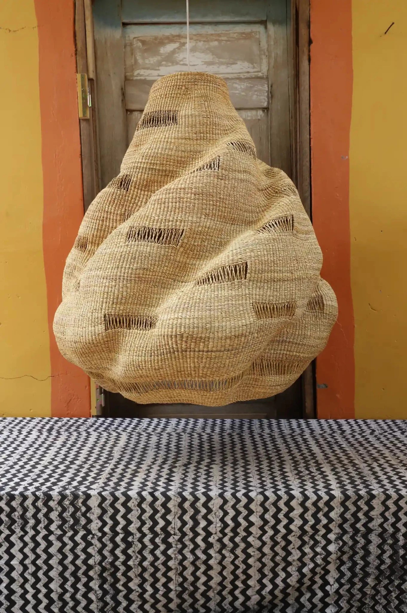 Woven basket hanging above a table with a patterned tablecloth.