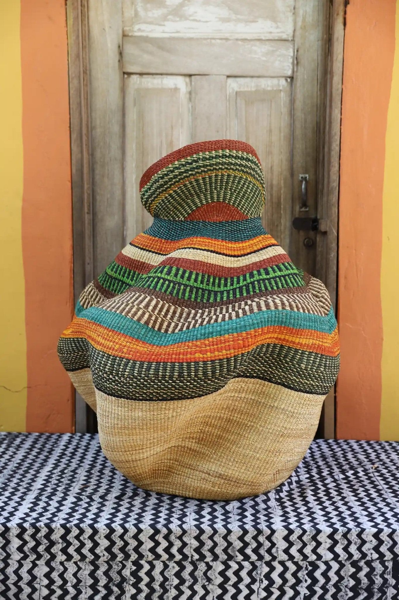 Decorative basket  on a black and white cloth against a wooden door.
