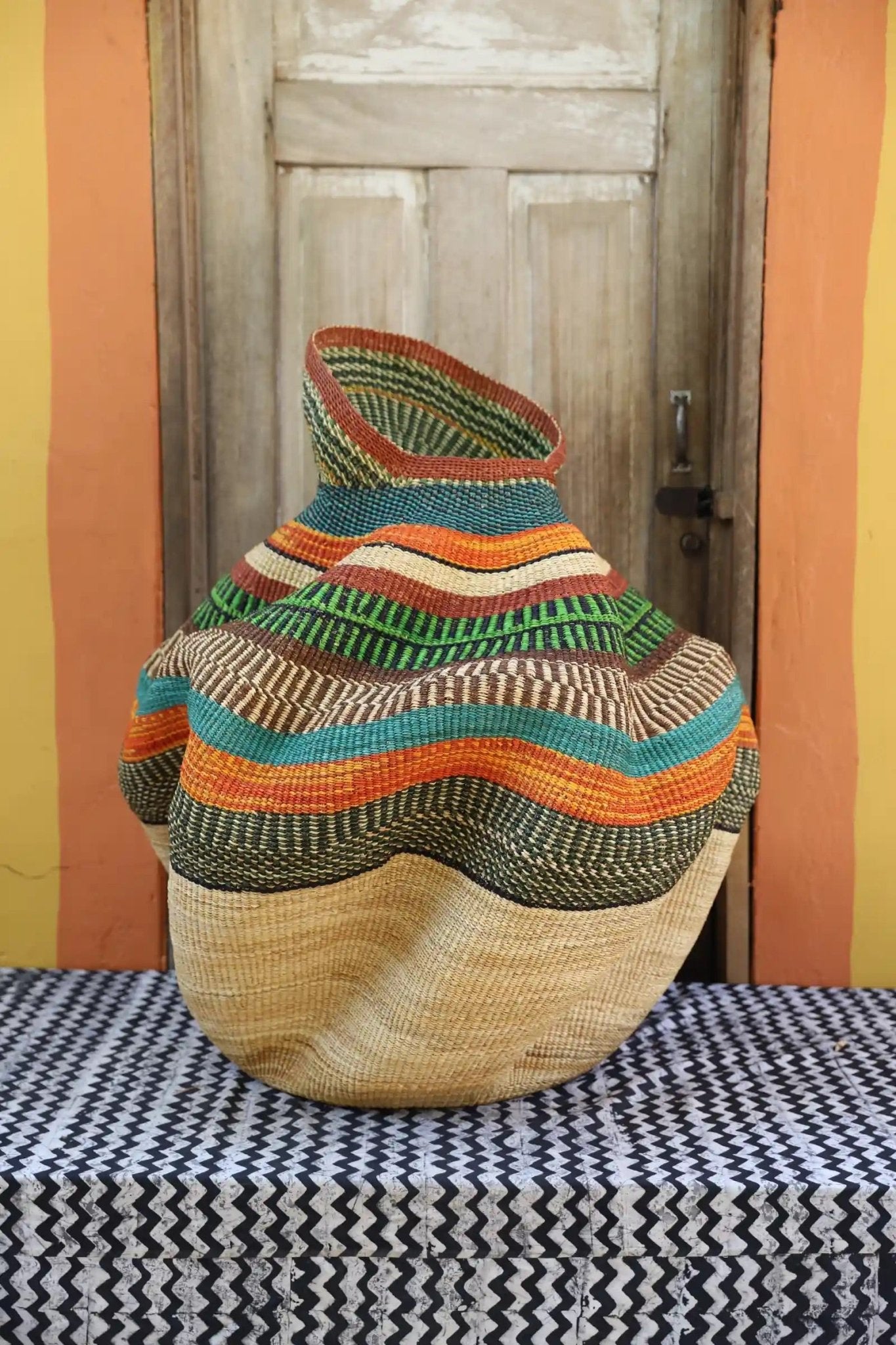 Decorative basket  on a black and white cloth against a wooden door.