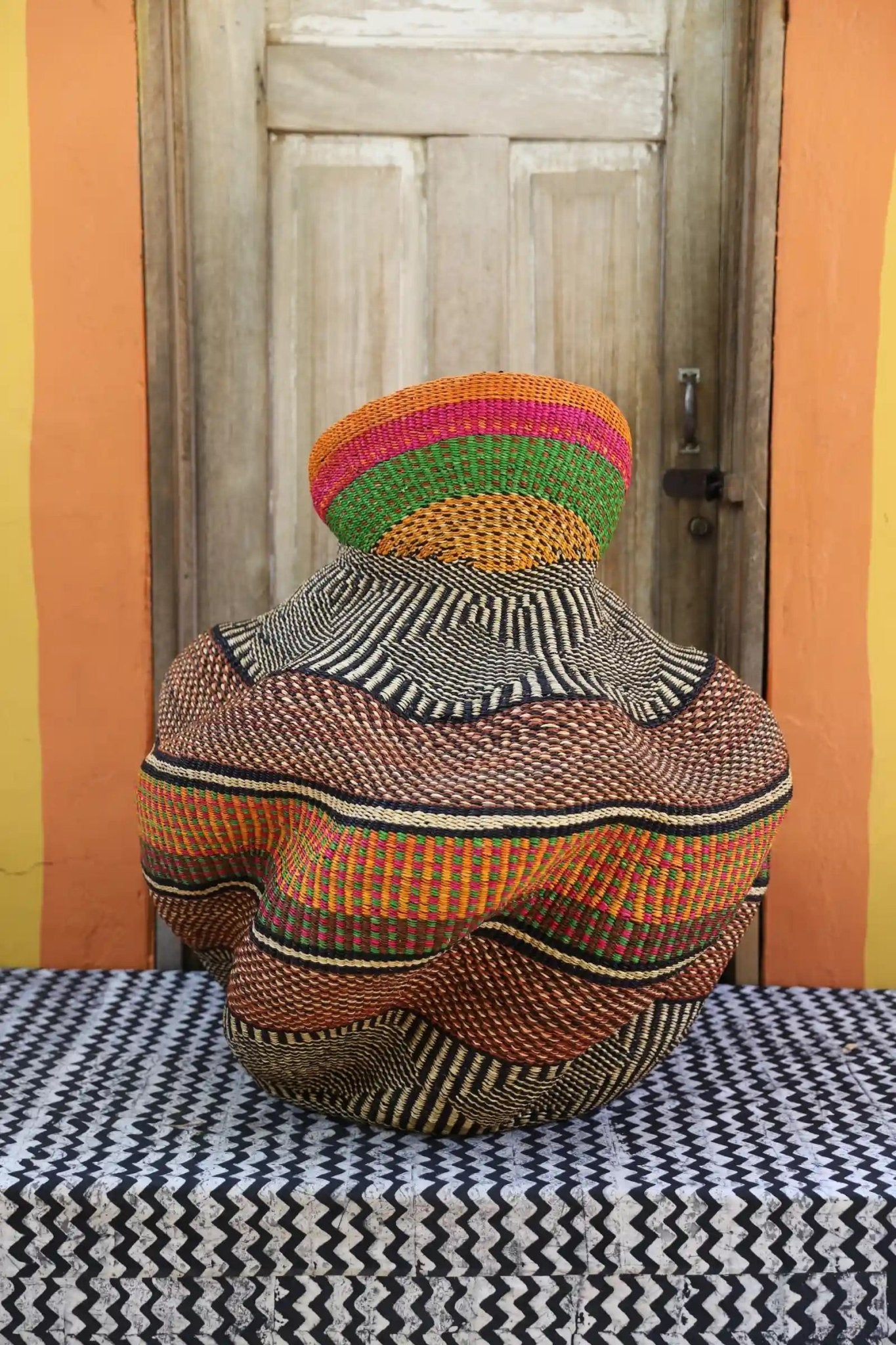 Decorative basket  on a black and white cloth against a wooden door.