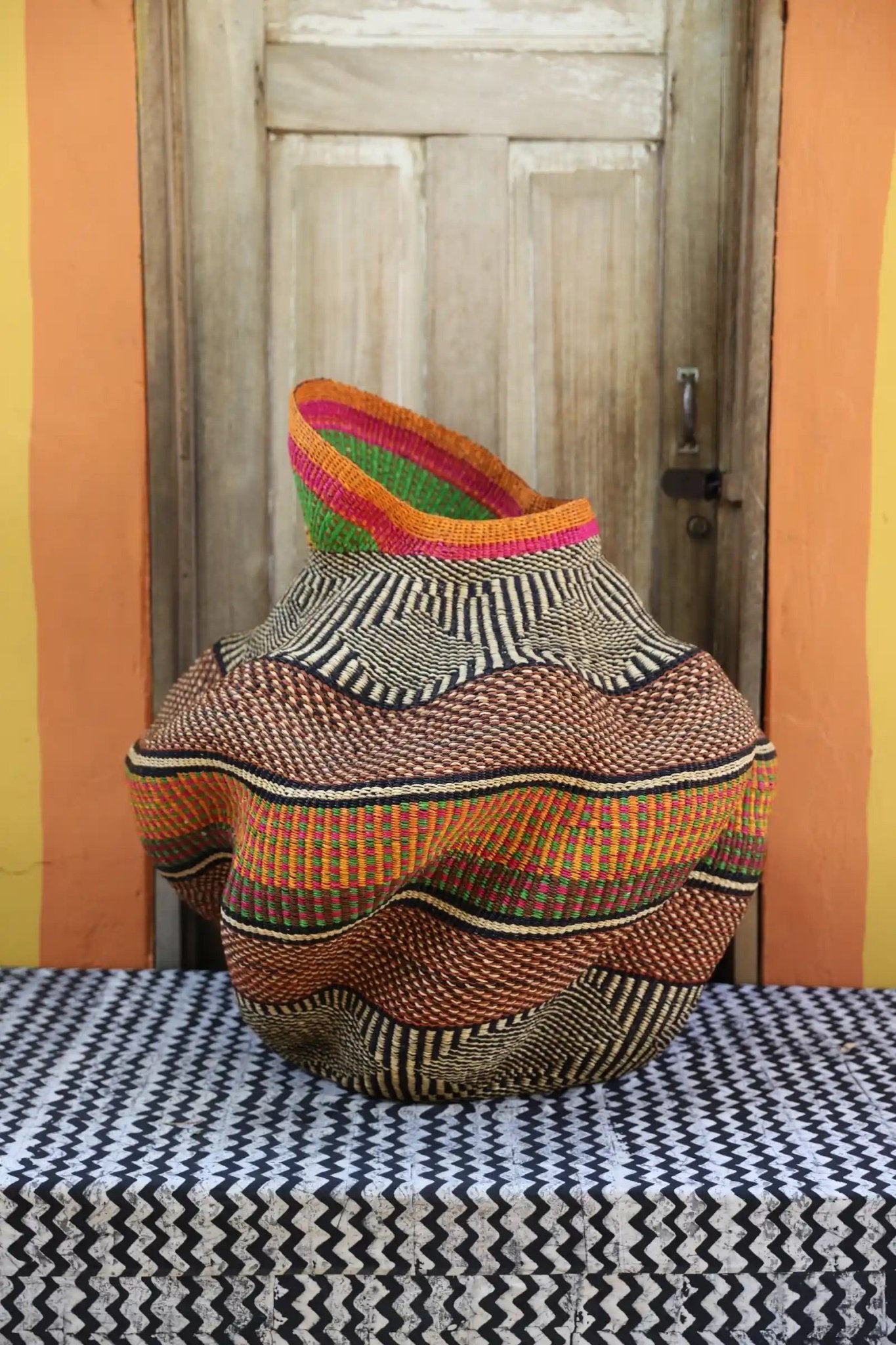Decorative basket  on a black and white cloth against a wooden door.