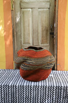 Textured orange and black woven basket on a table with a wooden door in the background
