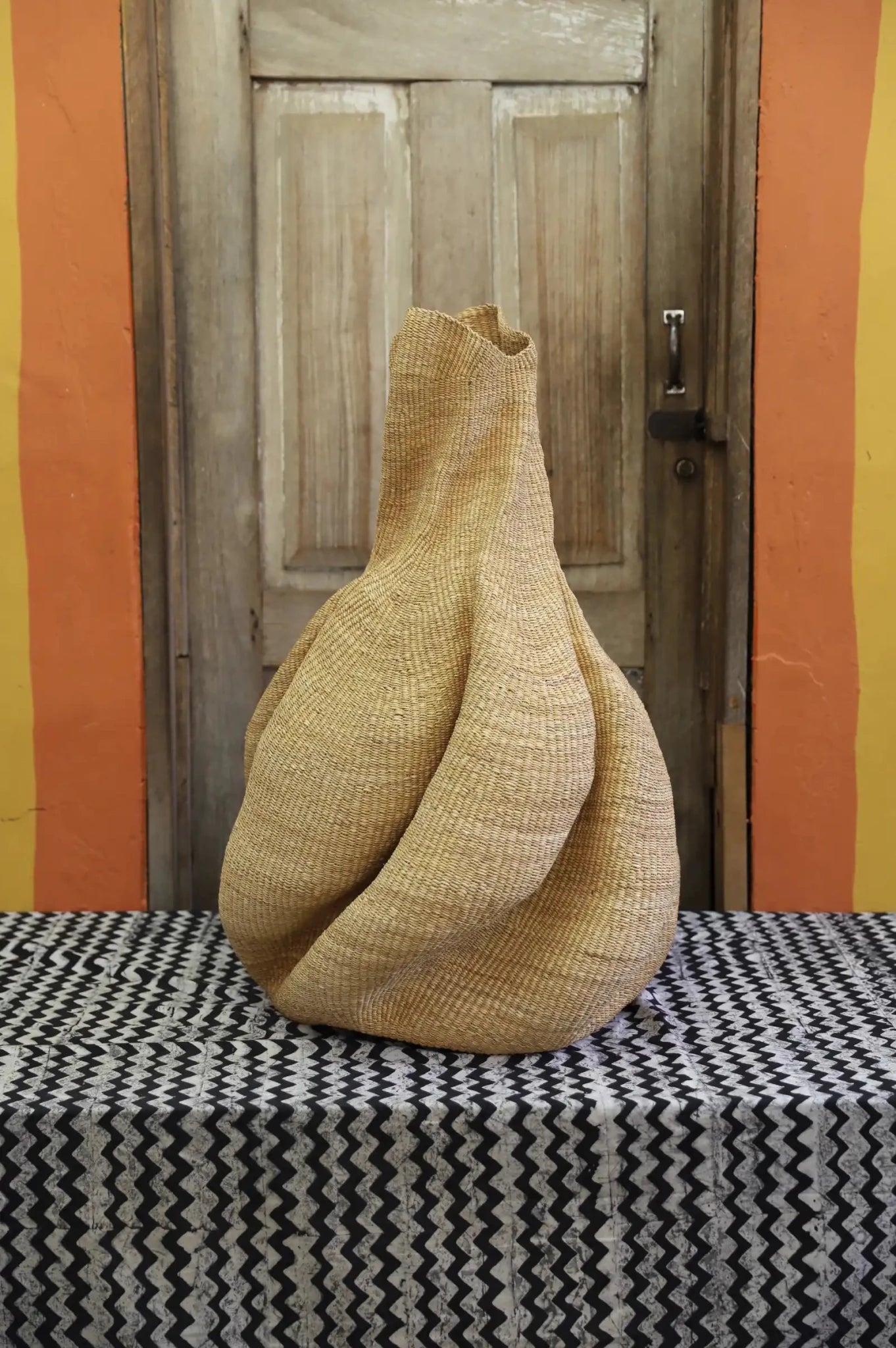 Decorative basket  on a black and white cloth against a wooden door.