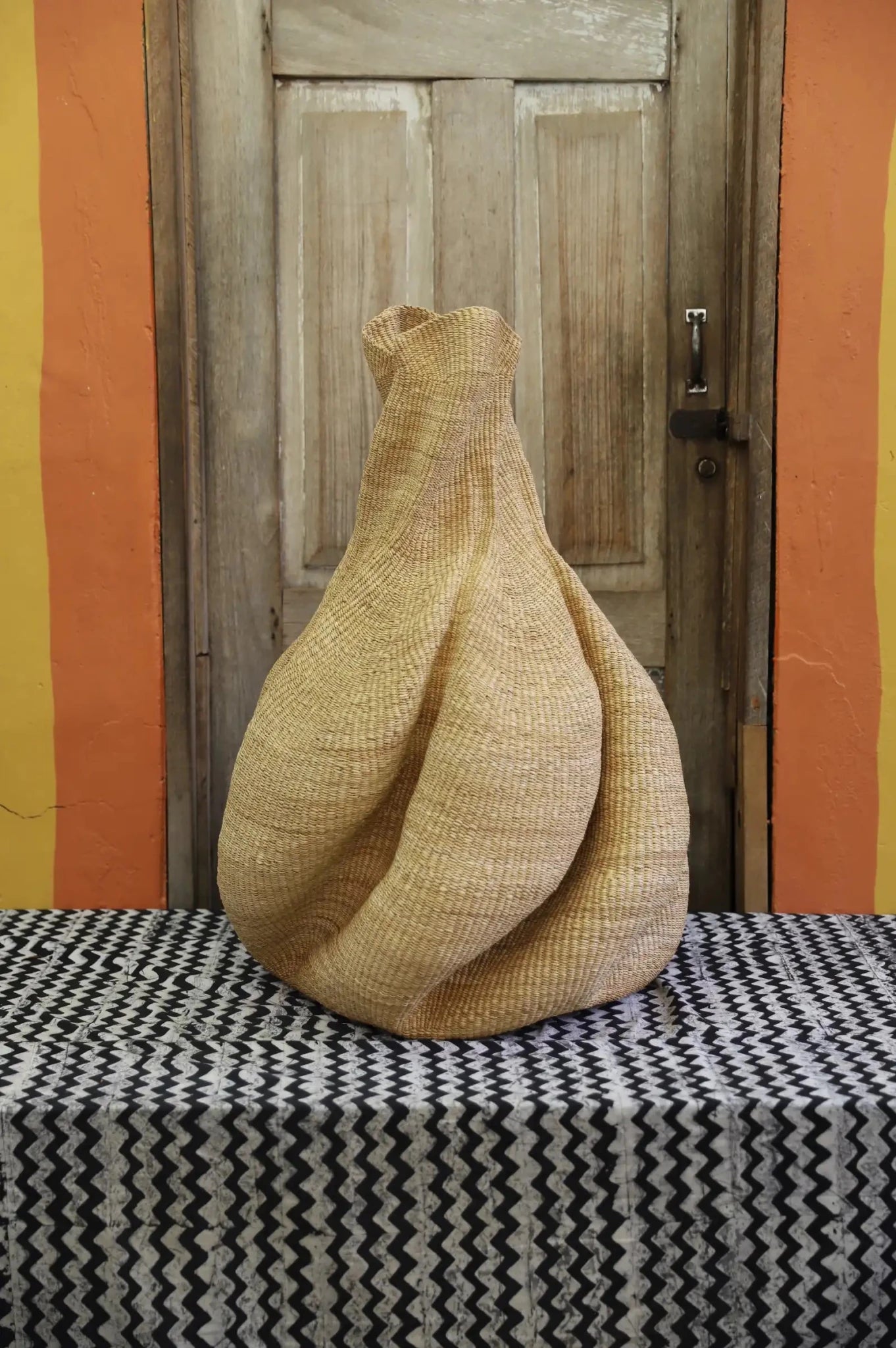 Decorative basket  on a black and white cloth against a wooden door.