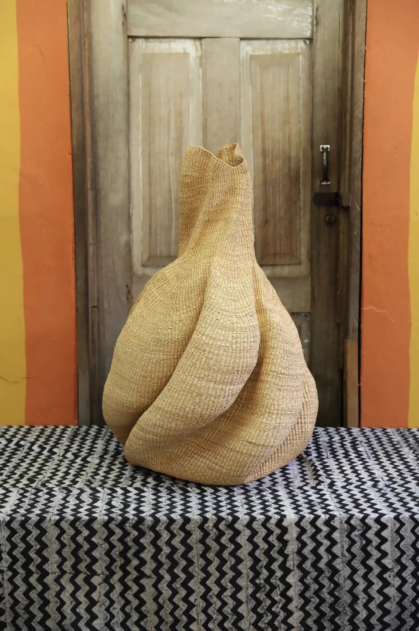 Decorative basket  on a black and white cloth against a wooden door.
