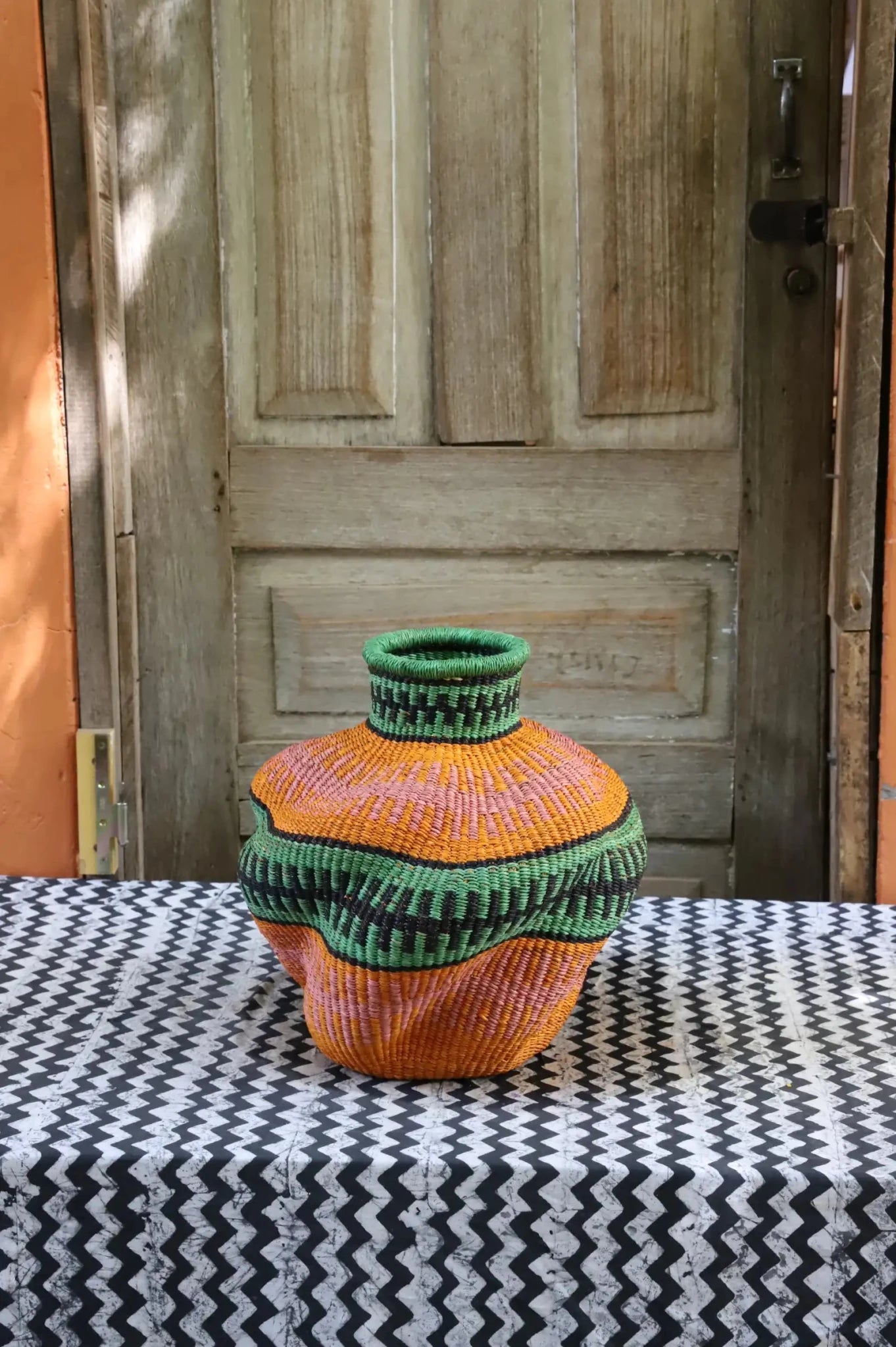 Colorful woven basket against a yellow wall.